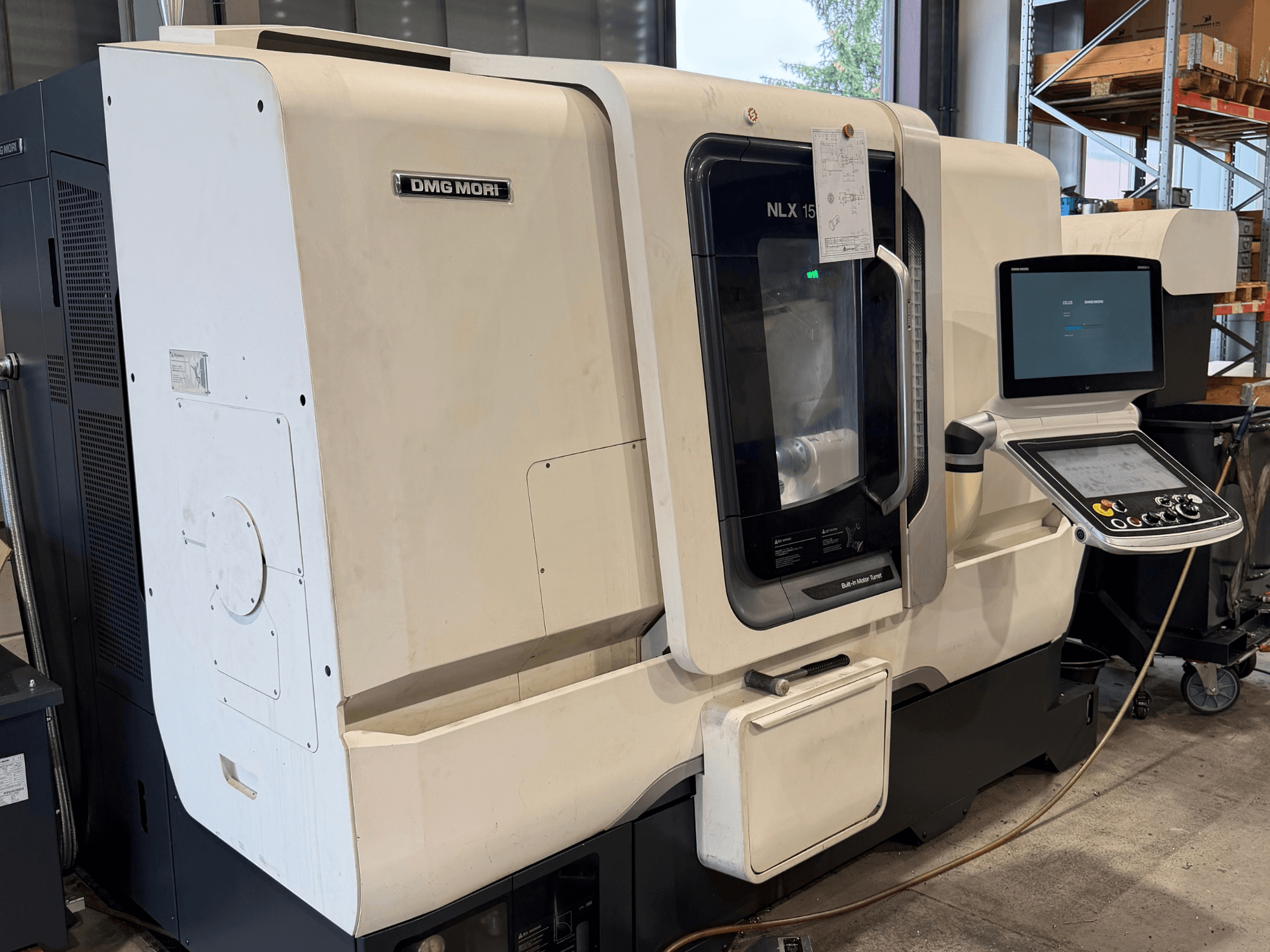 Vooraanzicht van de horizontale draaibank DMG MORI NLX1500MC/500, waarbij het bedieningspaneel en het spilgedeelte door de transparante afdekking heen te zien zijn.