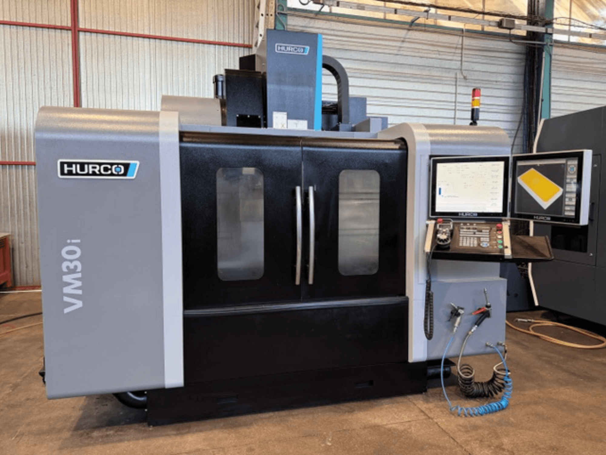Hurco VM30i verticaal bewerkingscentrum, vooraanzicht met bedieningspaneel, beeldschermen en machinedeuren.