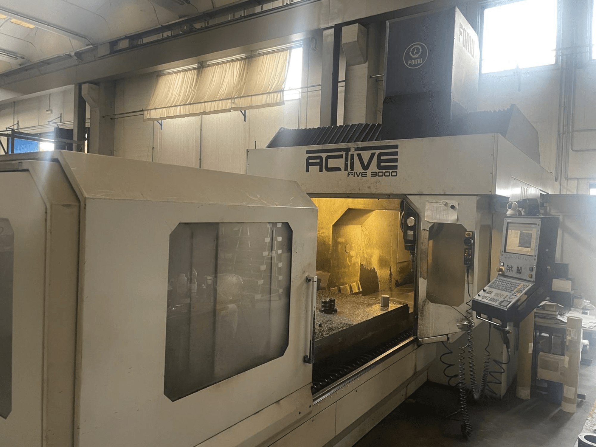 Vooraanzicht van ACTIVE Five 3000 CNC machine, met bedieningspaneel en werkgebied met gedeeltelijk bewerkt werkstuk binnenin.