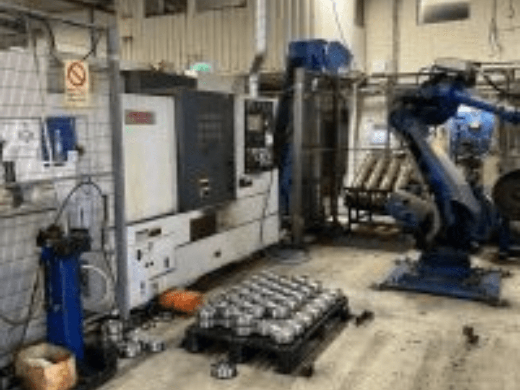 Horizontaal zicht van MORI SEIKI NL 2500 MC/700 draaimachine met robotarm en metalen onderdelen op de vloer.