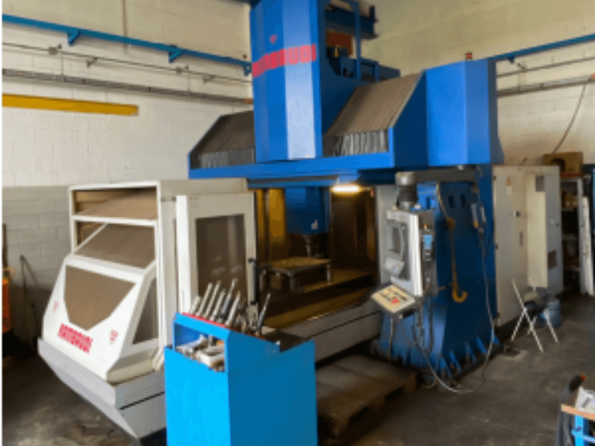 Verticaal bewerkingscentrum Rambaudi RF103, vooraanzicht met bedieningselementen, gereedschapopslag en bewerkingsgebied. Blauwe en witte buitenkant.