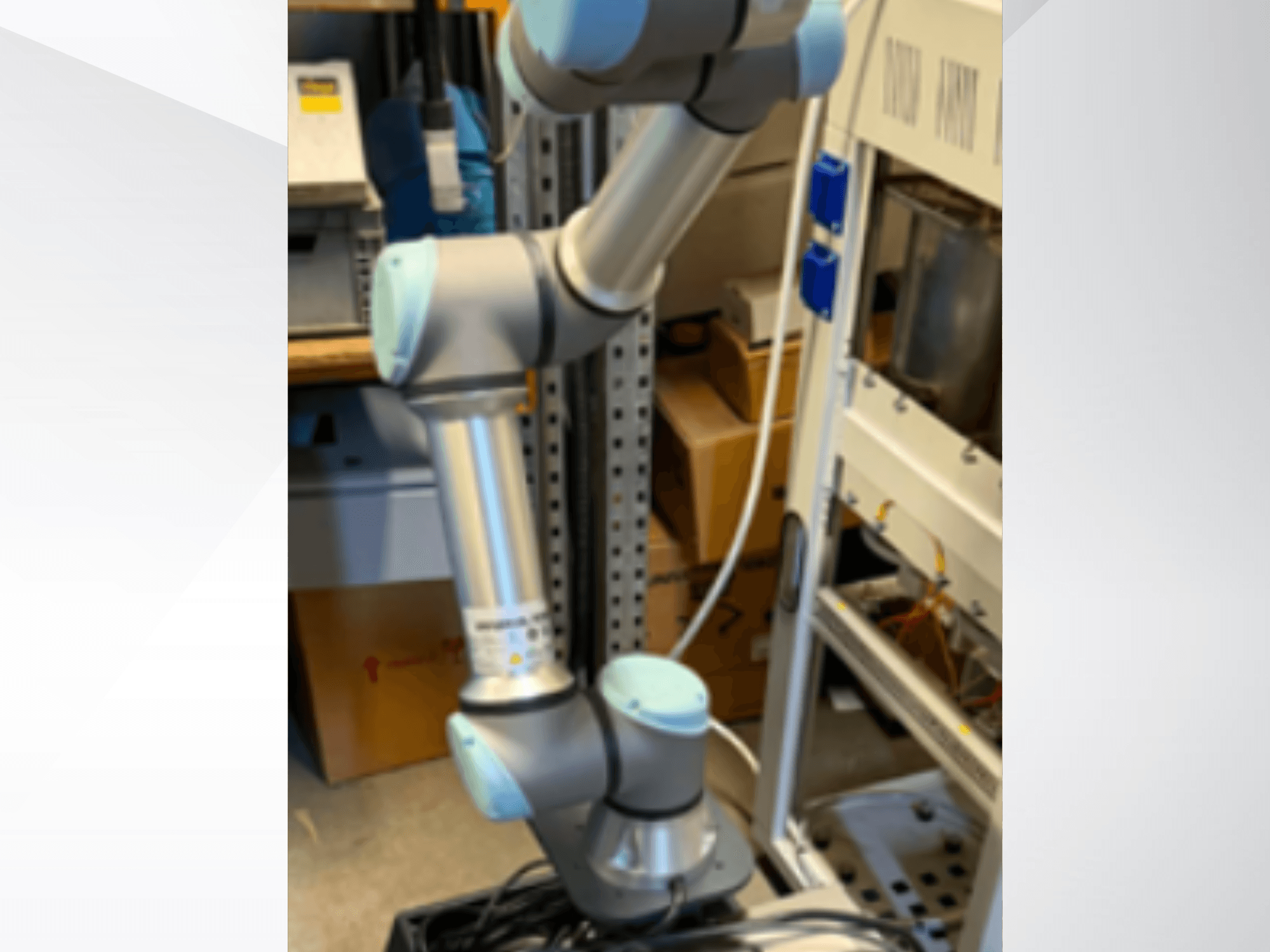 De UR5e-robotarm van Universal Robots, gezien vanaf de zijkant, met zichtbare scharniergewrichten, een lichtgewicht ontwerp en besturingskabels.