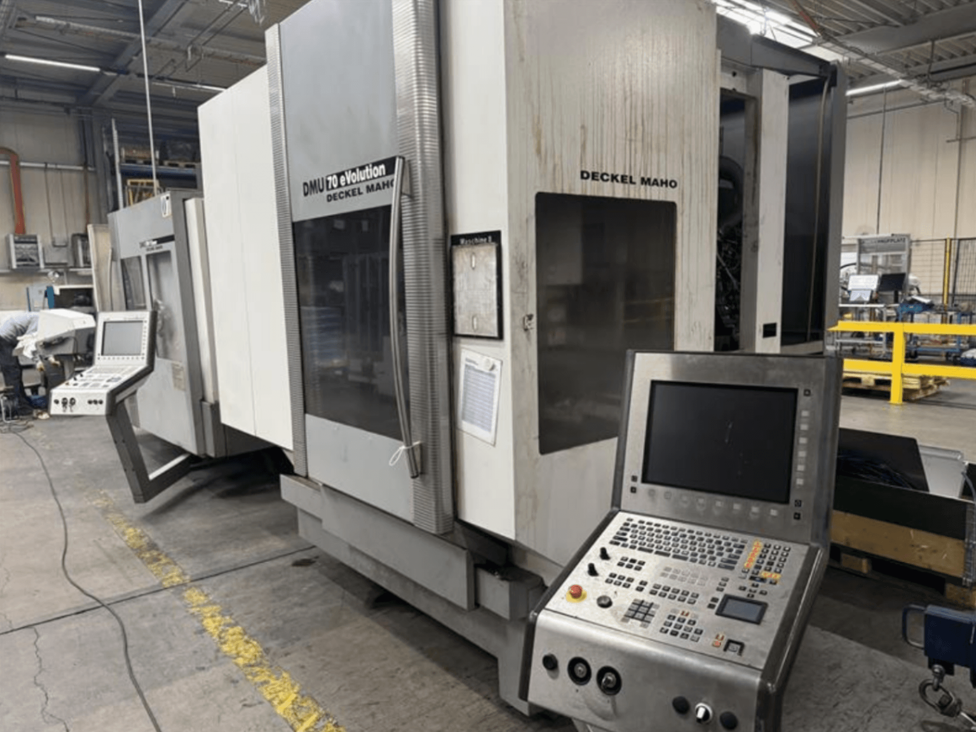 Vooraanzicht van een Deckel Maho DMU 70 eVOLUTION CNC machine met bedieningspaneel, in een productiefaciliteit.