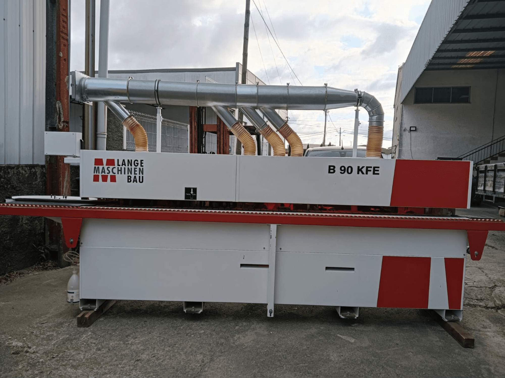 LANGE Maschinenbau B 90 KFE-kantenlijmmachine in zijaanzicht met dubbele uitlaatpijpen en rode accenten, geplaatst in een industriële werkruimte.