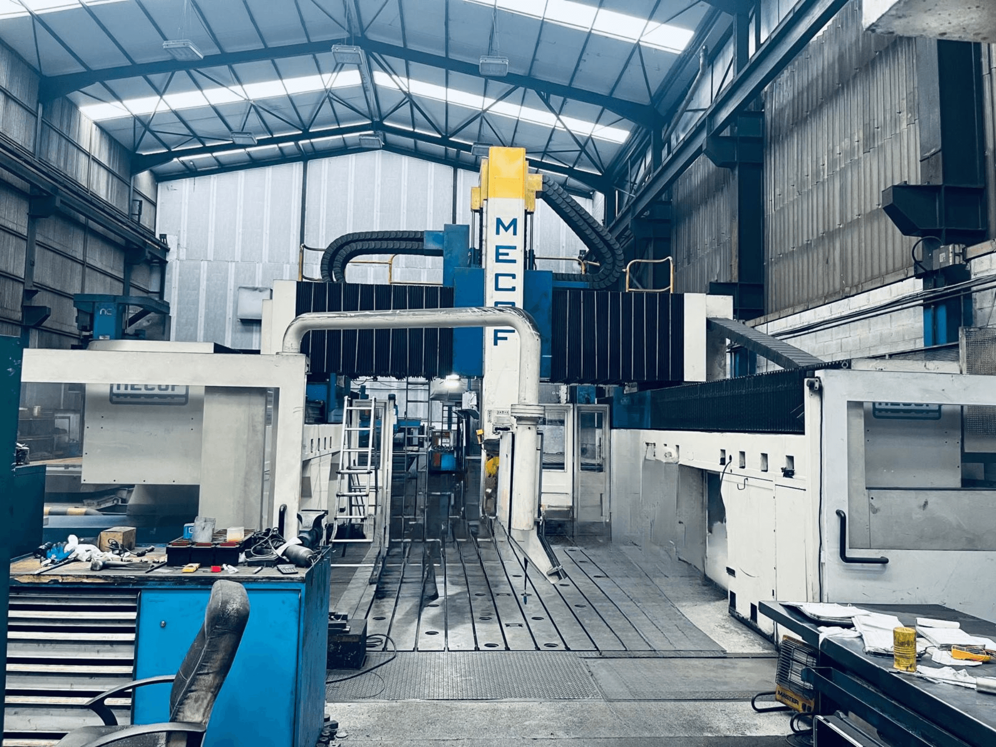MECOF DYNAMILL 3000L-portalfreesmachine in de werkplaats, vooraanzicht, met blauw-witte constructie, gereedschappen en werkruimte.
