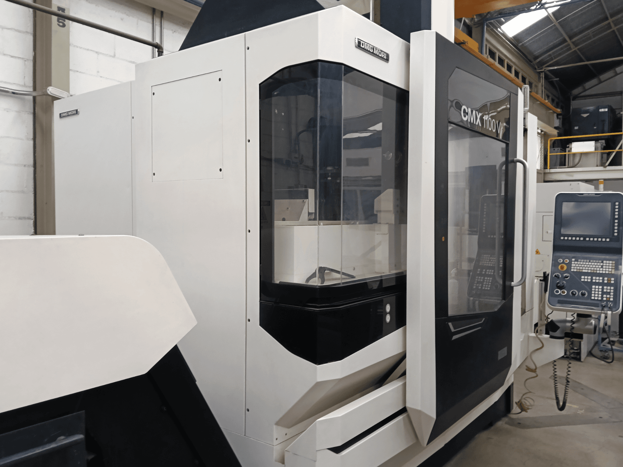 DMG MORI MORI CMX 1100 V verticaal bewerkingscentrum, vooraanzicht, met het bedieningspaneel en de glazen behuizing.