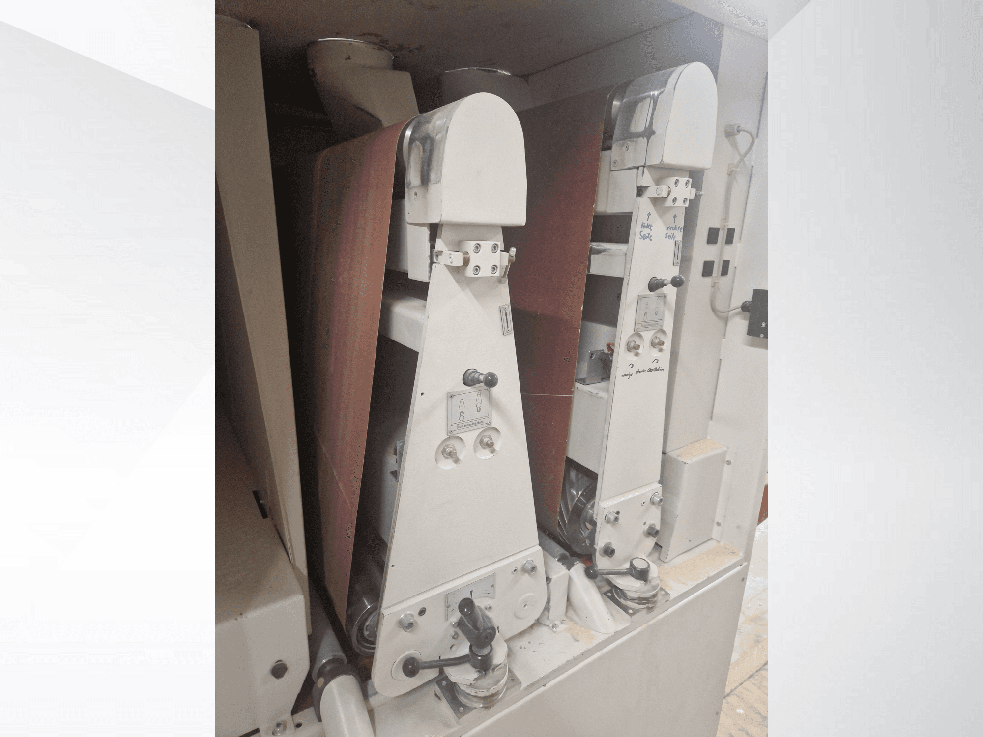 Twee industriële schuurmachines met rode schuurbanden, vooraanzicht, met de bedieningselementen en metalen onderdelen.