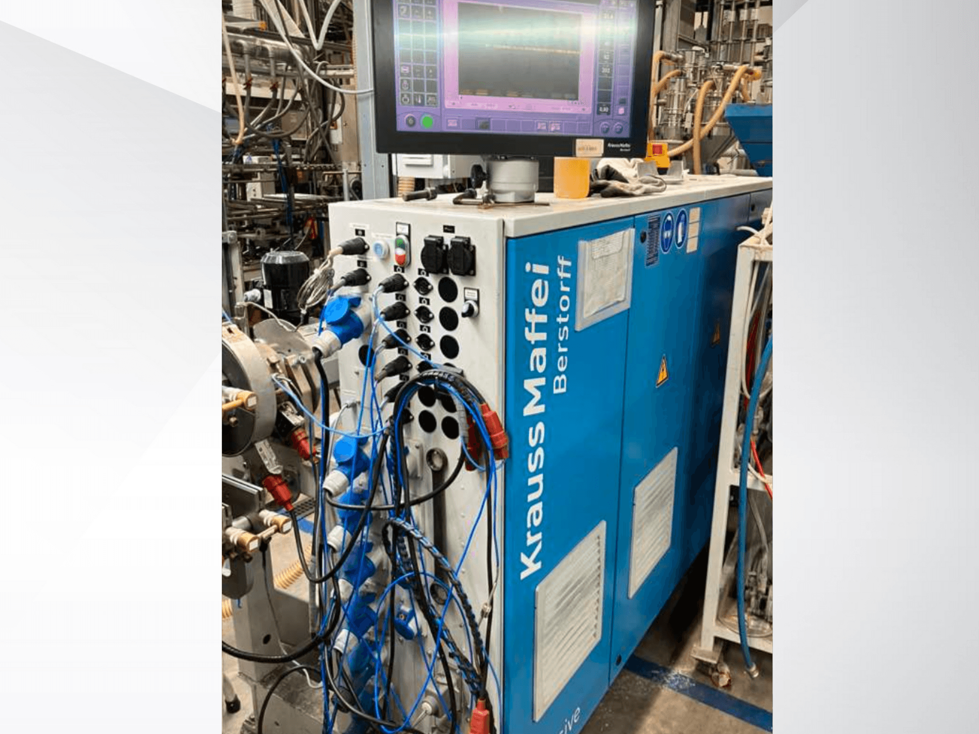 Krauss Maffei Berstorff industriële machine met bedieningspaneel en monitor, voorzien van diverse knoppen en aangesloten slangen, zijaanzicht.