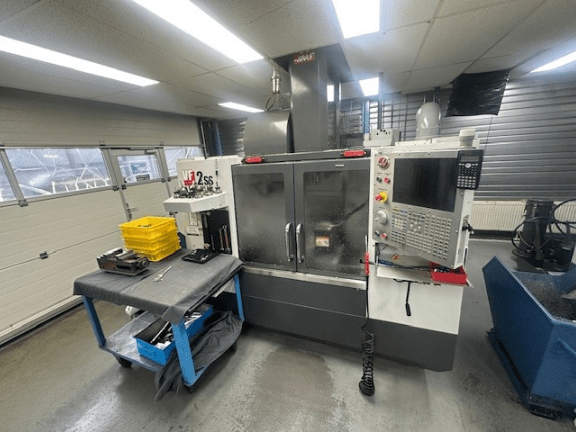 Vooraanzicht van HAAS VF-2SS verticaal bewerkingscentrum met bedieningspaneel, werktafel en gereedschapsmagazijn.
