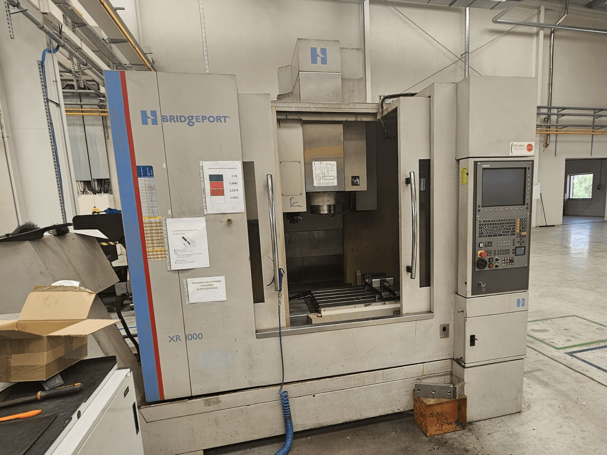 Bridgeport XR 1000 verticaal bewerkingscentrum, vooraanzicht, met een bedieningspaneel en zichtbaar werkgebied met een snijtafel.