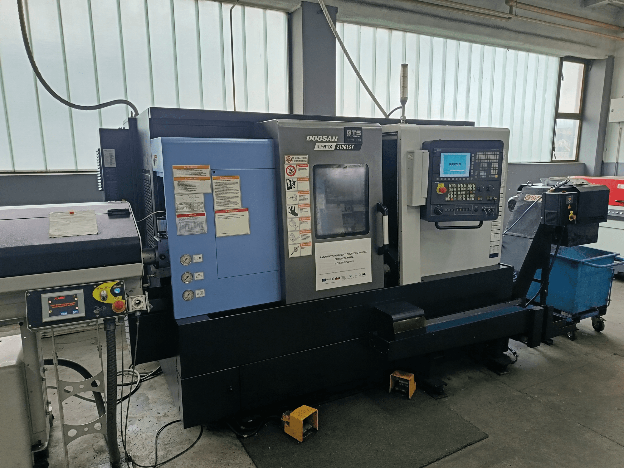 DOOSAN LYNX 2100 LSY draaimolencentrum, zijaanzicht met bedieningspaneel en bedieningsknoppen, met zichtbare informatielabels.