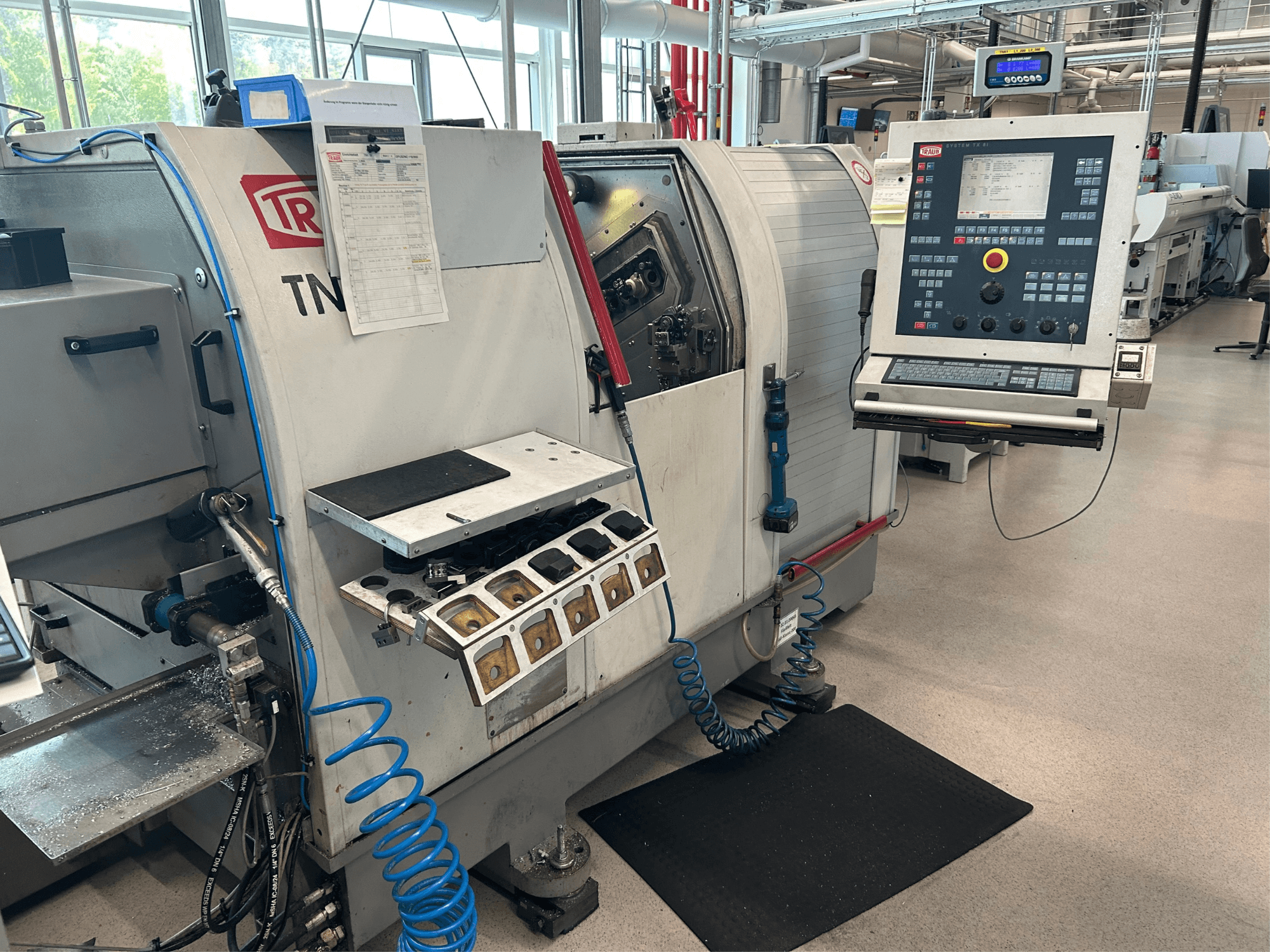 Horizontale draaimachine TRAUB TNK 36, vooraanzicht, met het bedieningspaneel, de gereedschapshouder en het werkgebied met metaalspanen.