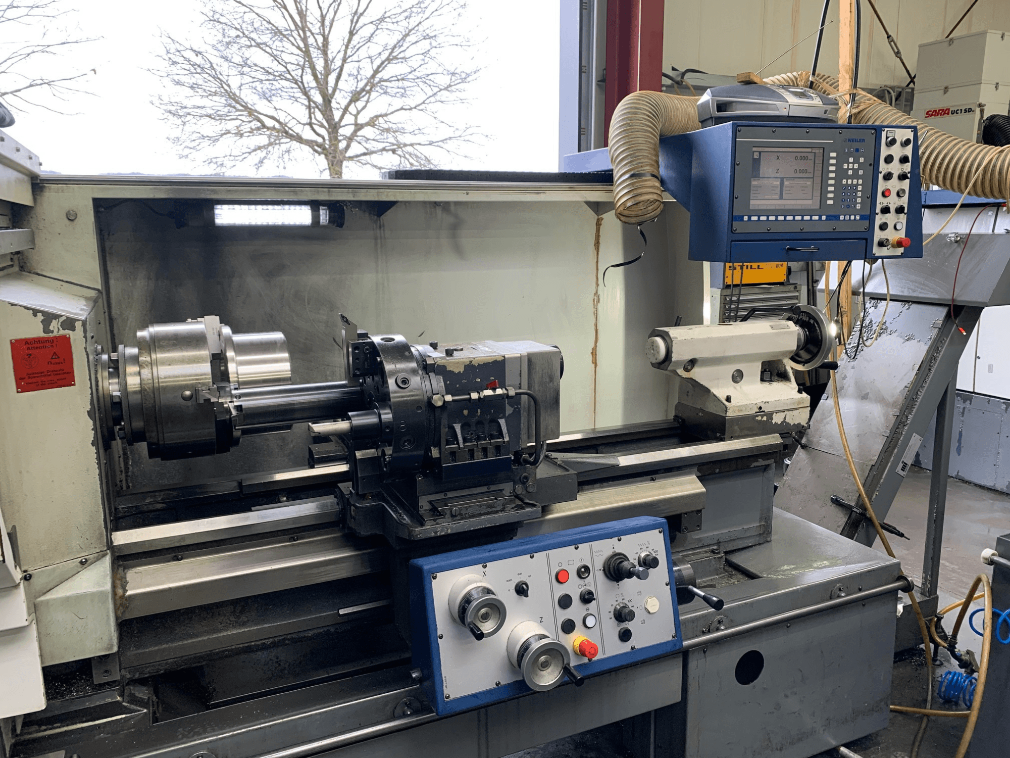 Weiler E55X1000 horizontale draaimachine in een werkplaats, met het bedieningspaneel, de draaibank en de gereedschapshouder. Vooraanzicht.