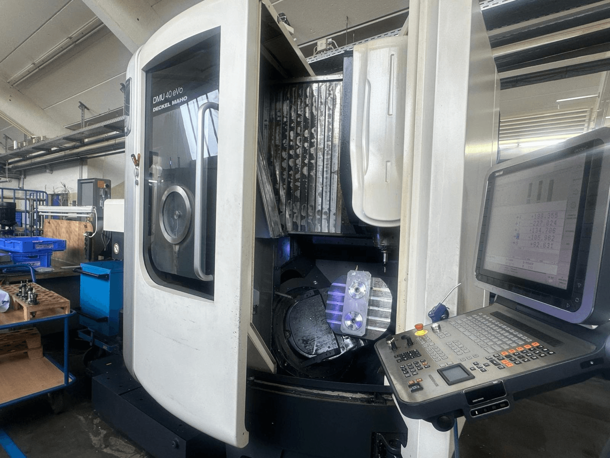 DMU 40 eVo freesmachine van Deckel Maho in een werkplaats, vooraanzicht, met bedieningspaneel en metalen stuk in de spindel.