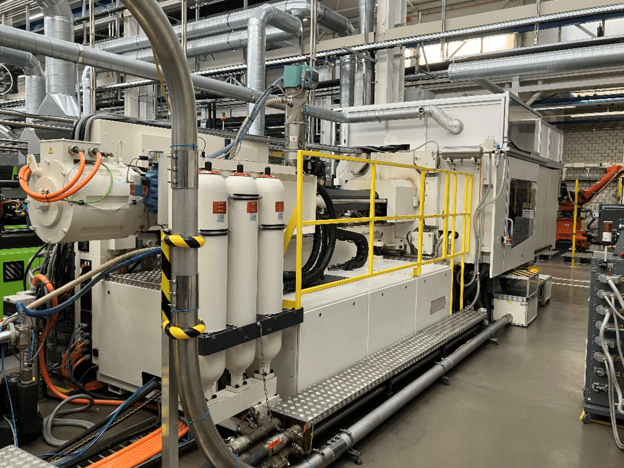 Industriële machine met witte en grijze behuizing, meerdere slangen en filtertanks; zijaanzicht toont operationele opstelling.