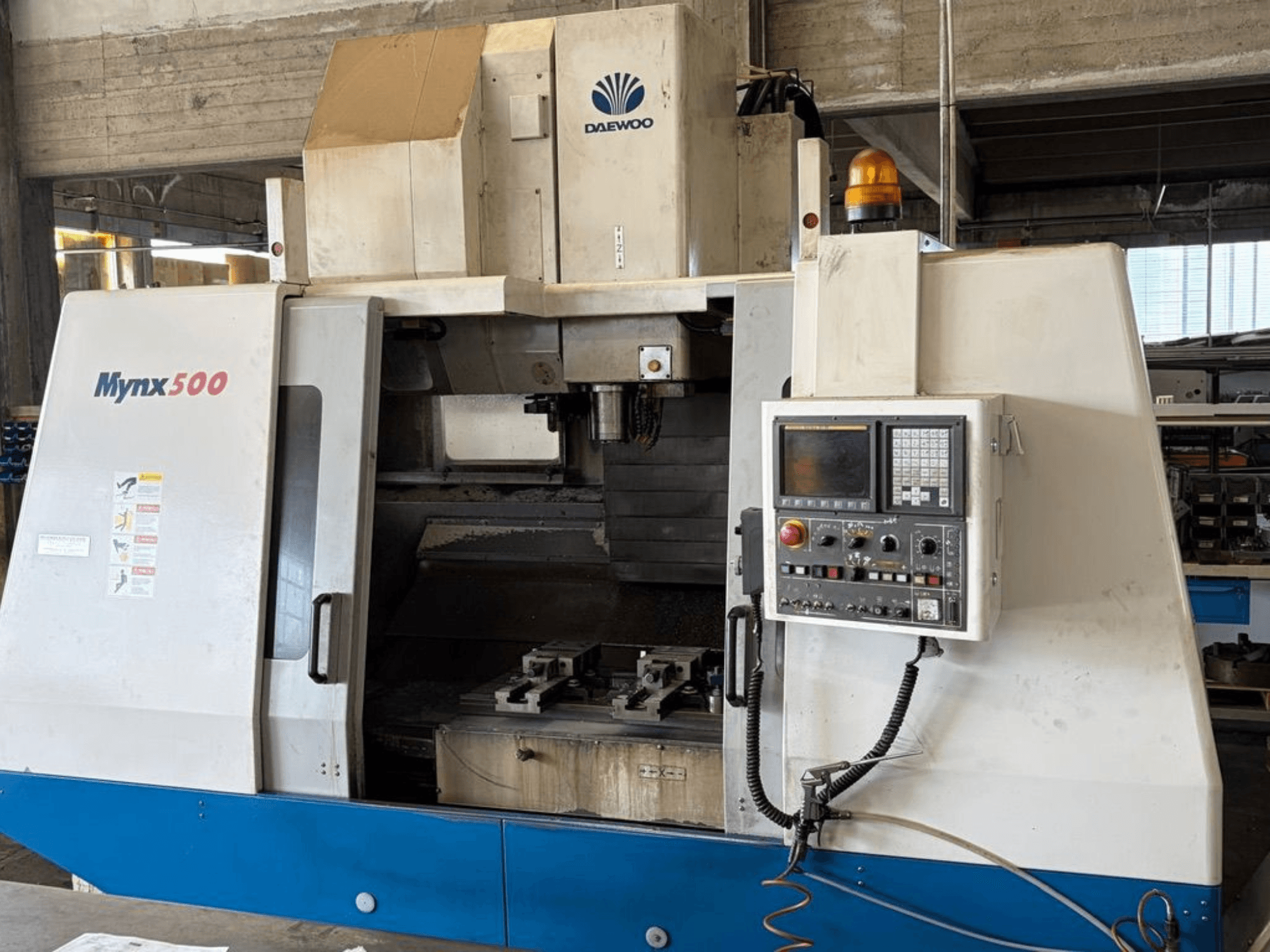Het verticale bewerkingscentrum DAEWOO Mynx 500, gezien vanaf de voorkant, met een bedieningspaneel en een gereedschapshouder aan de binnenkant.