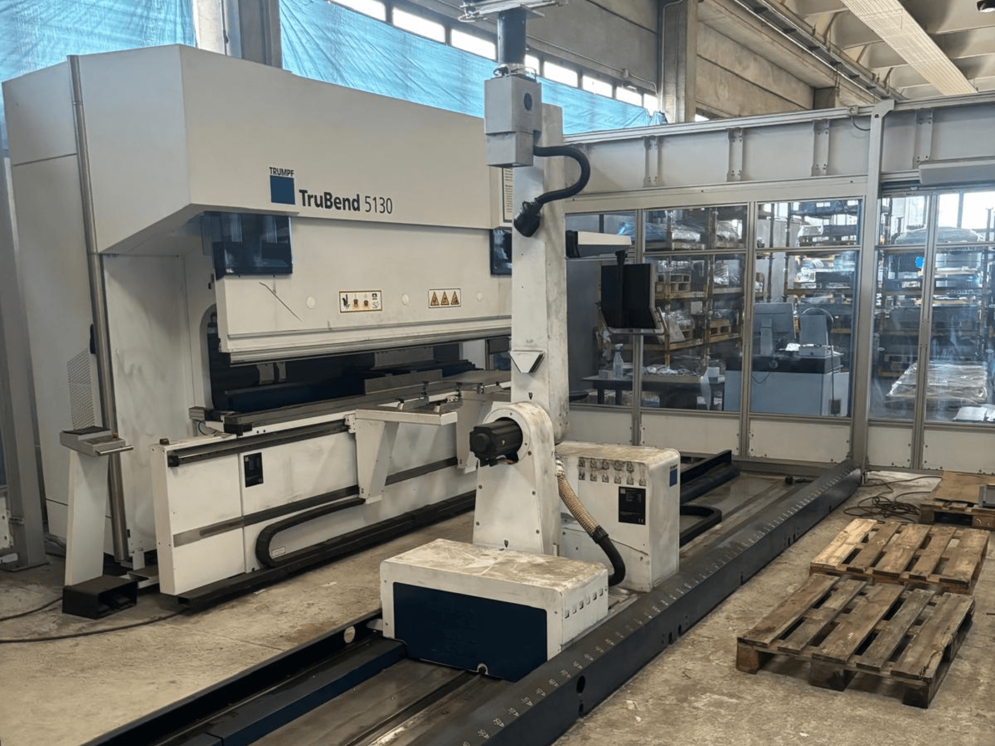 TruBend 5130 buigmachine van Trumpf, vooraanzicht, met bedieningspaneel en pallets in een fabrieksomgeving.