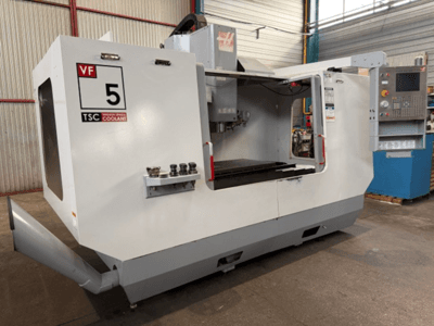 HAAS VF5-HE verticaal bewerkingscentrum, vooraanzicht, met het TSC-koelsysteem en het bedieningspaneel.