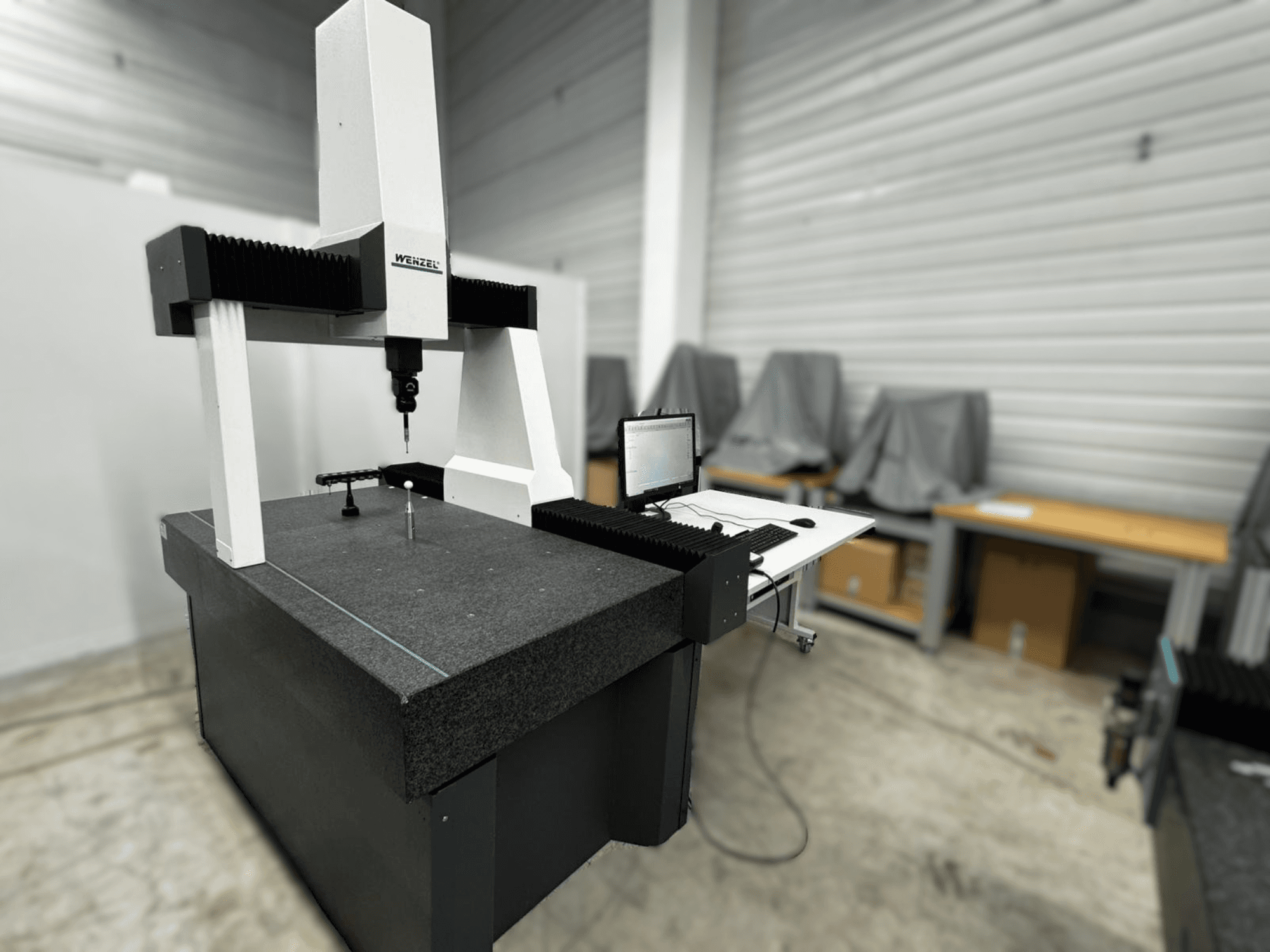 Wenzel LH 54 coördinatenmeetmachine in zijaanzicht, met een taster en een computerinterface op een grijze basis.