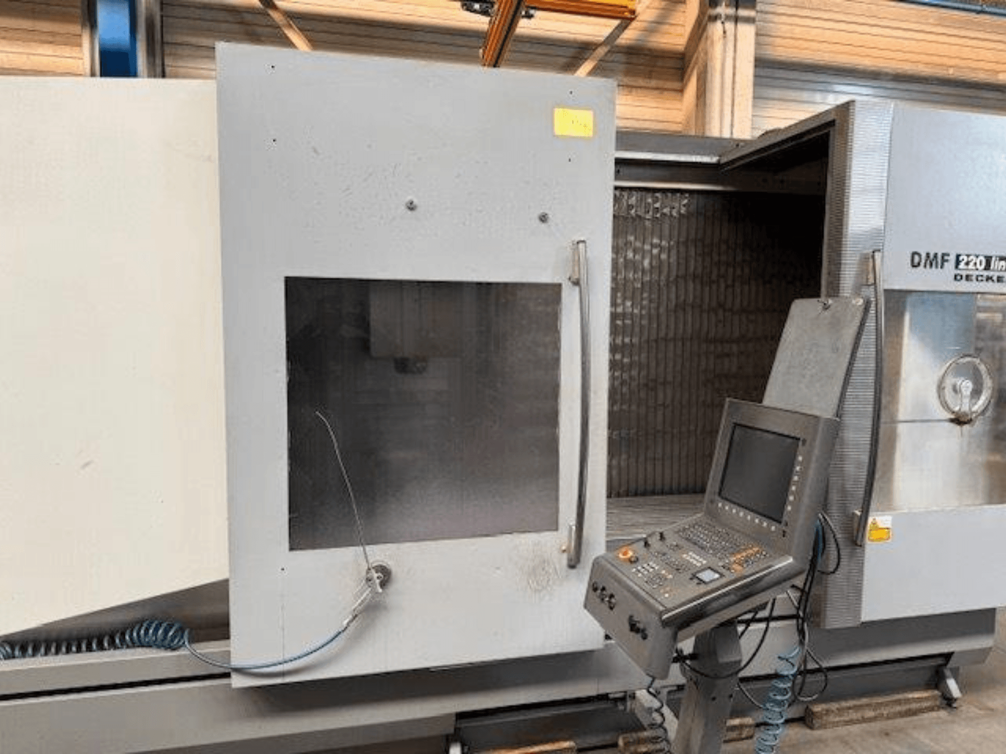 Vooraanzicht van DECKEL MAHO DMF 220 Lineair verticaal bewerkingscentrum, met het bedieningspaneel en de geopende machinedeur.