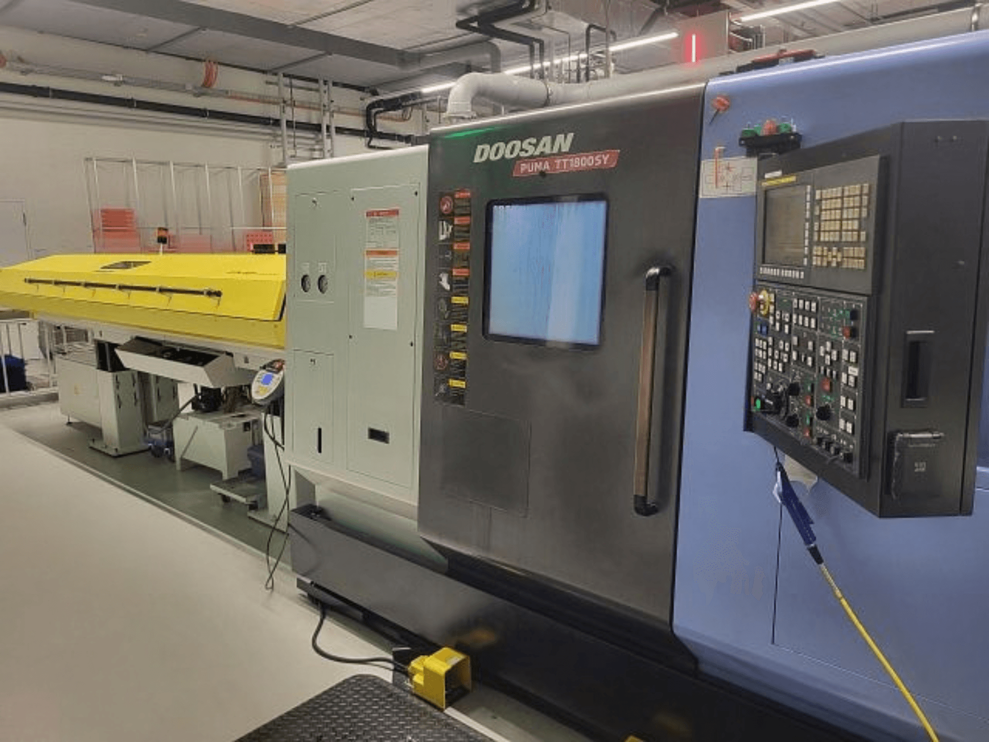 DOOSAN PUMA TT 1800 SY frees- en draaicentrum, vooraanzicht met bedieningspaneel en gele afdekking, industriële omgeving.