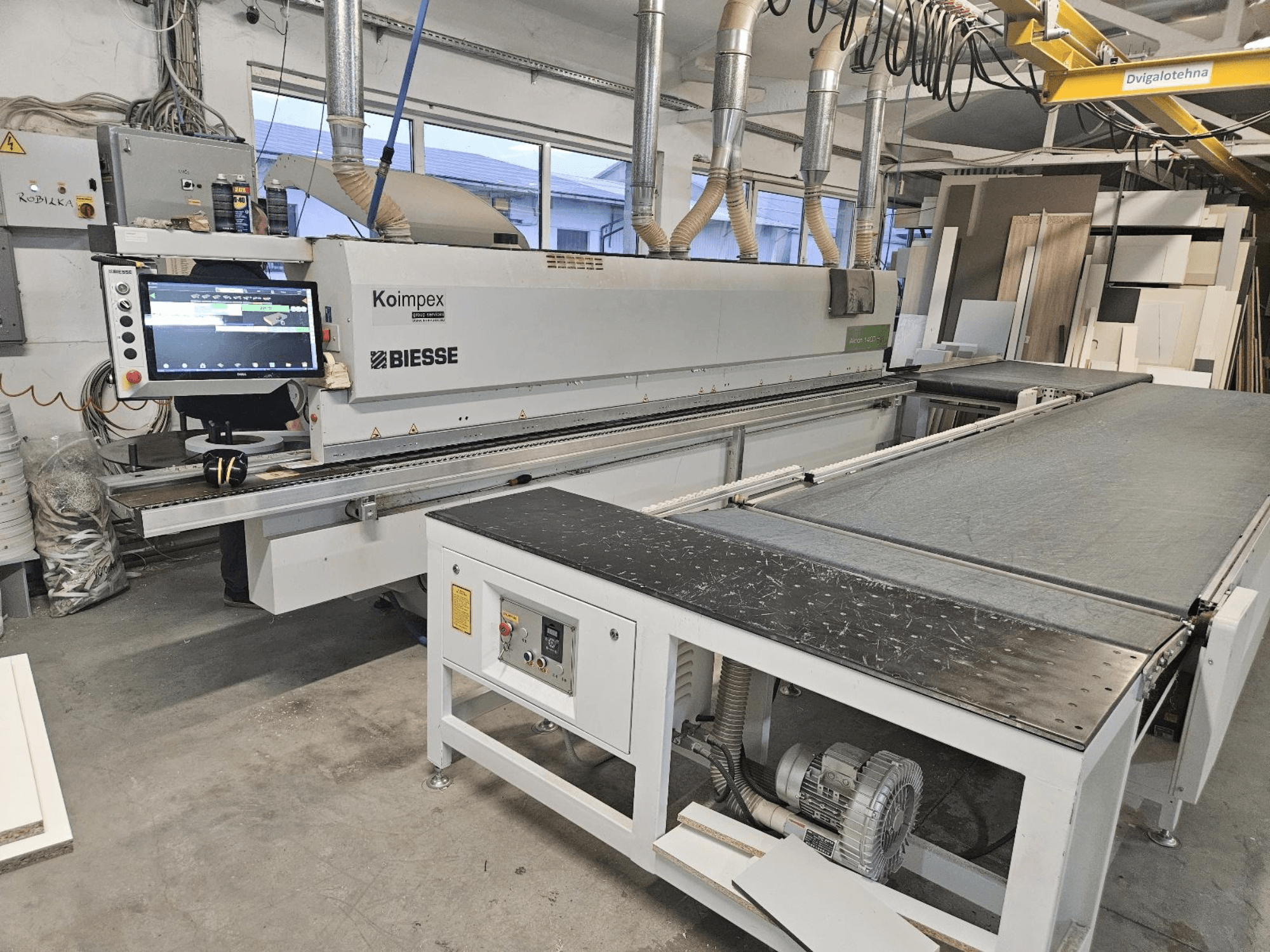 BIESSE Akron 1440 Een kantenbewerkingsmachine in een werkplaats, zijaanzicht met bedieningspaneel en transportband.
