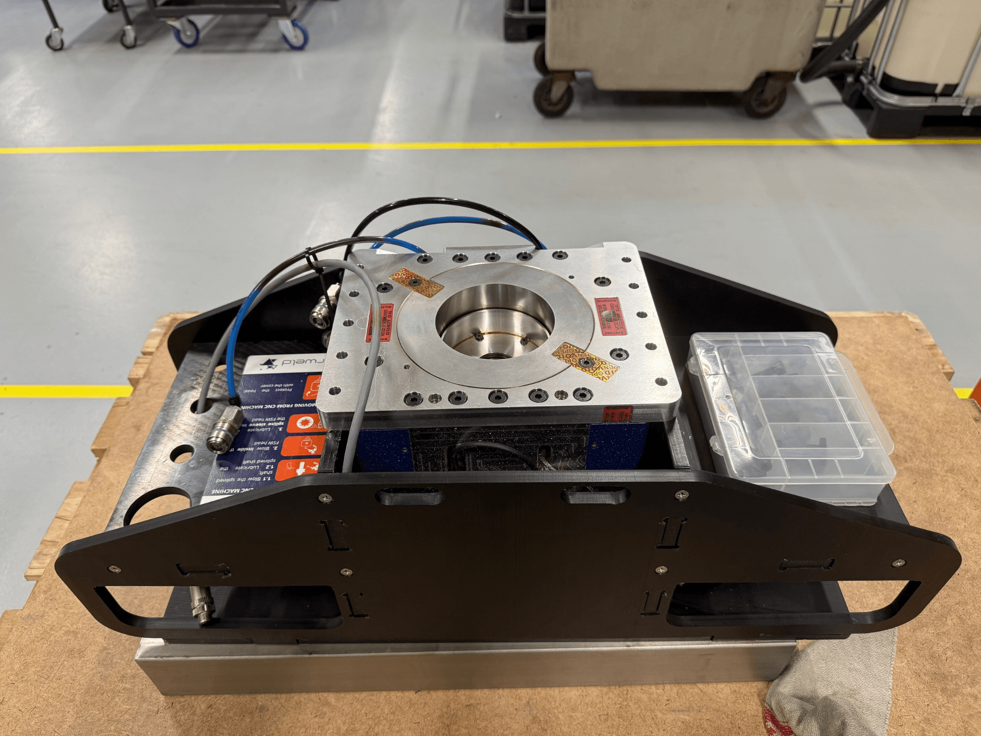 Machinaal bewerkt metalen onderdeel met blauwe kabels, accessoirebehuizing en platte basis, bovenaanzicht, ideaal voor mechanische toepassingen.