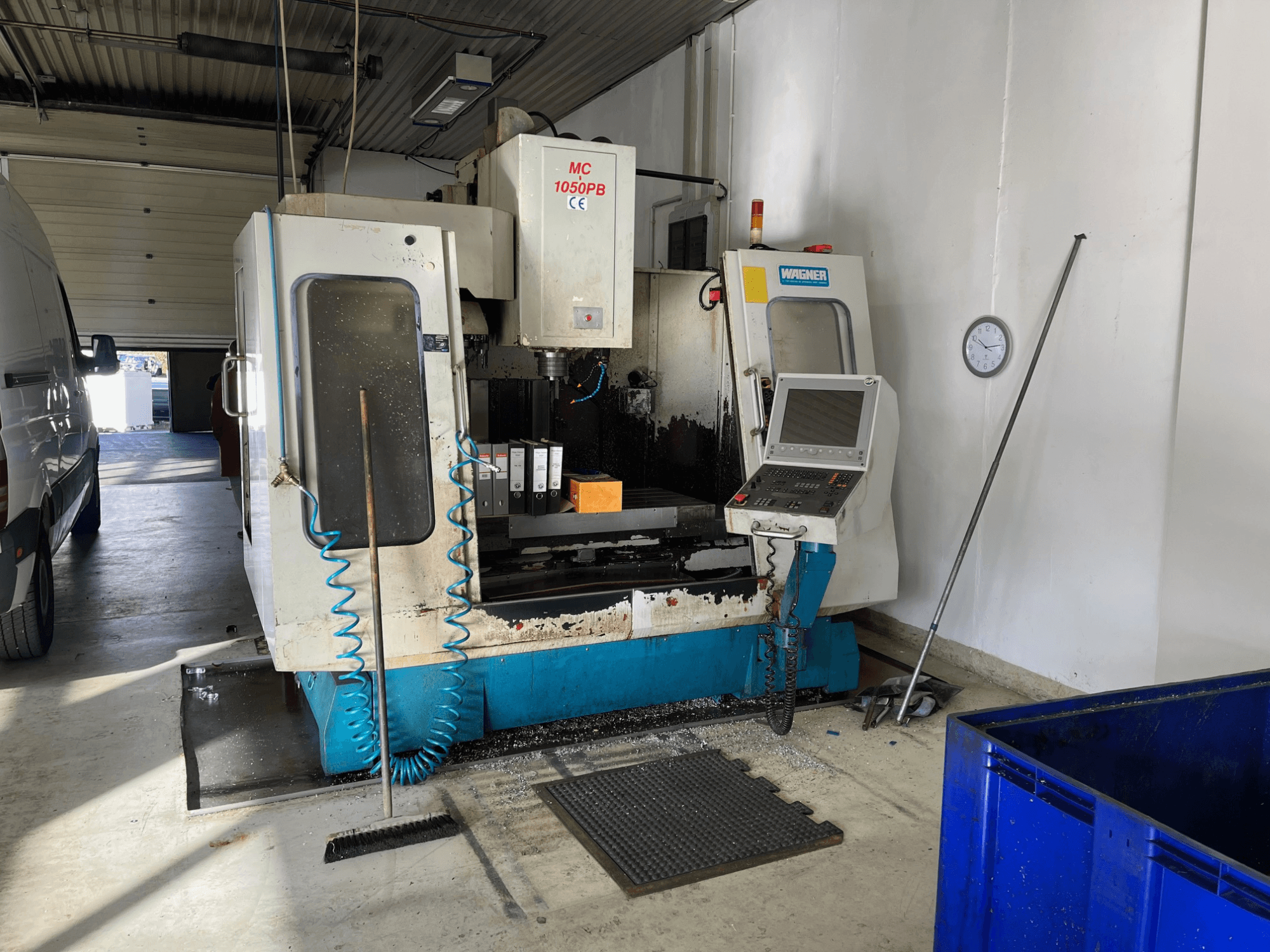WAGNER MC 1050PB CNC machine in werkplaats, vooraanzicht, met bedieningspaneel en werkgebied; blauwe luchtslang en reinigingsgereedschap zichtbaar.