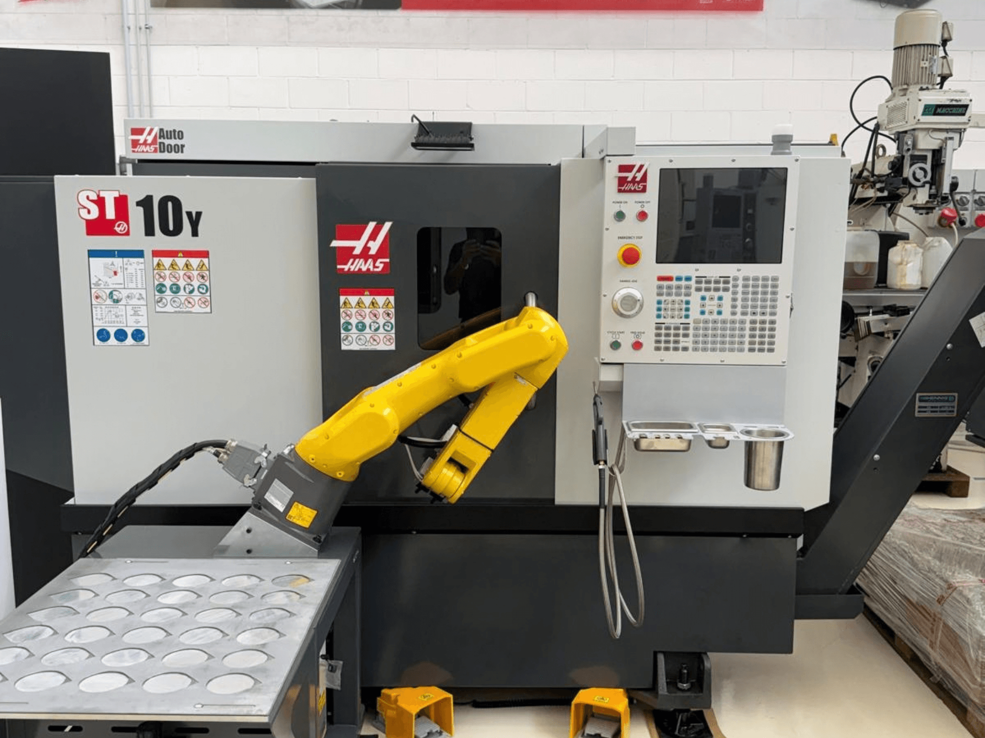 Haas ST-10Y horizontale draaibank, gezien vanaf de voorkant, voorzien van een robotarm en een bedieningspaneel met gereedschapshouders.