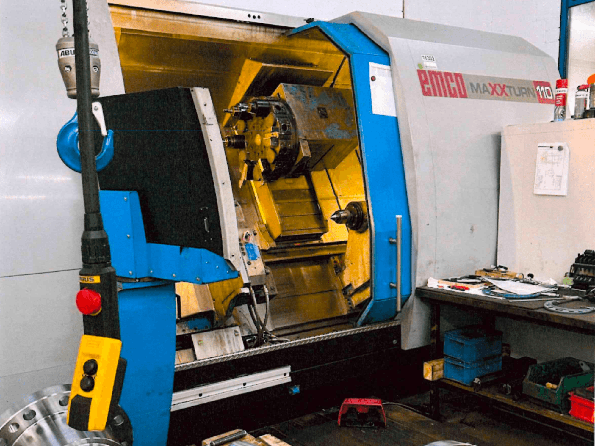 Horizontale EMCO MAXTURN 110-draaimachine, vooraanzicht, met zicht op de interne onderdelen en het bedieningspaneel, in een werkplaatsomgeving.