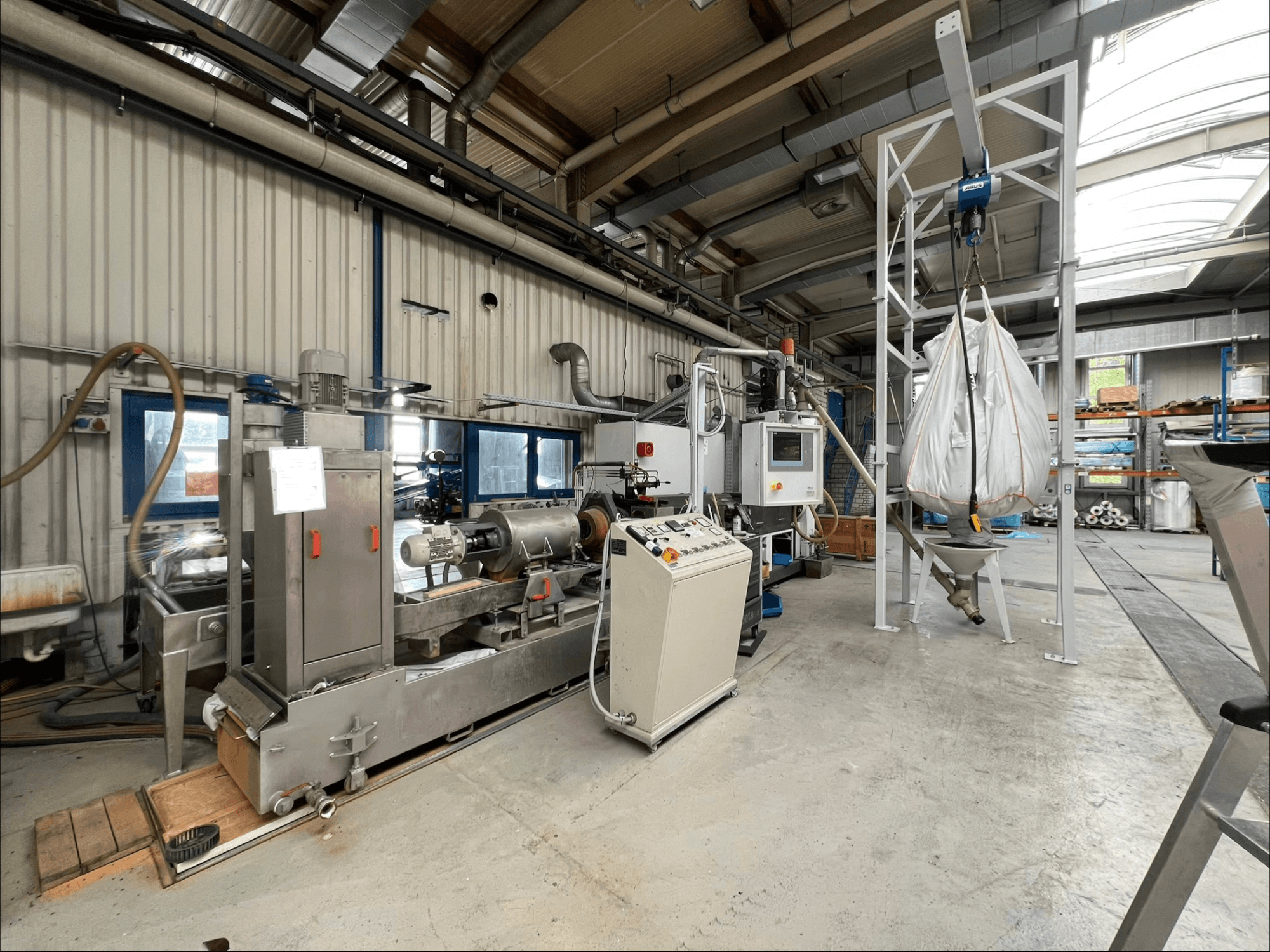 Vooraanzicht van de FILTEC GRP 350 kunststofverwerkingsmachine in een industriële omgeving, met bedieningselementen en toevoersysteem.
