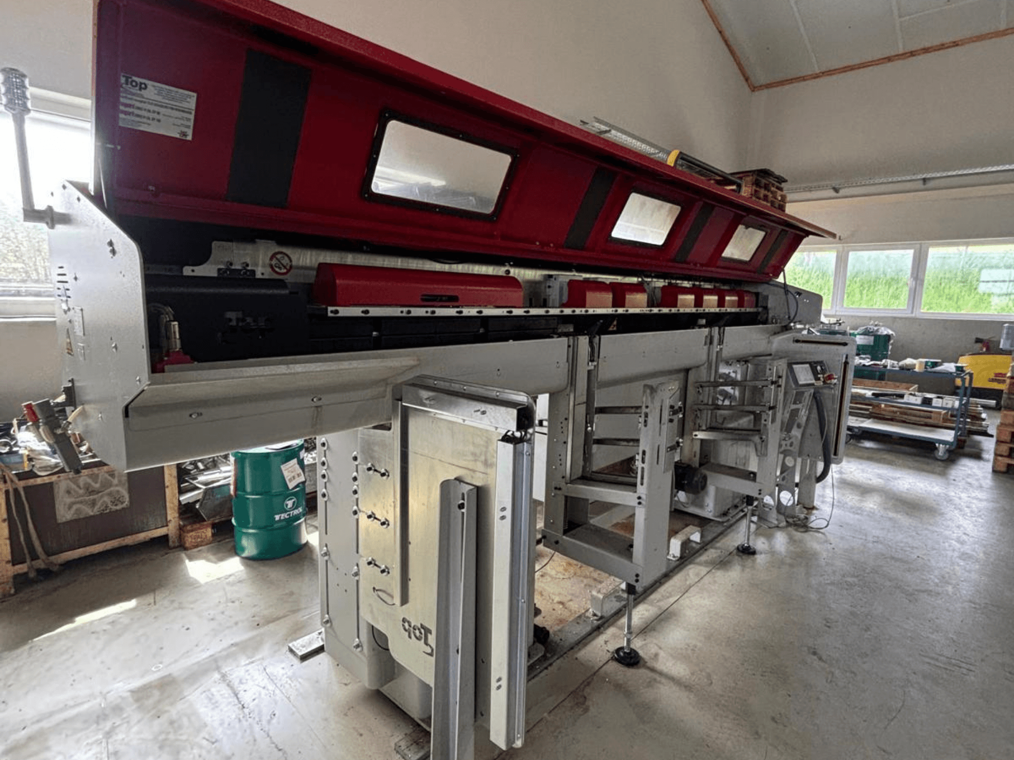 TOP Automazioni Top Loader ETL 10-75, gezien vanaf de zijkant, met een rood bovenste gedeelte en complexe mechanische onderdelen.