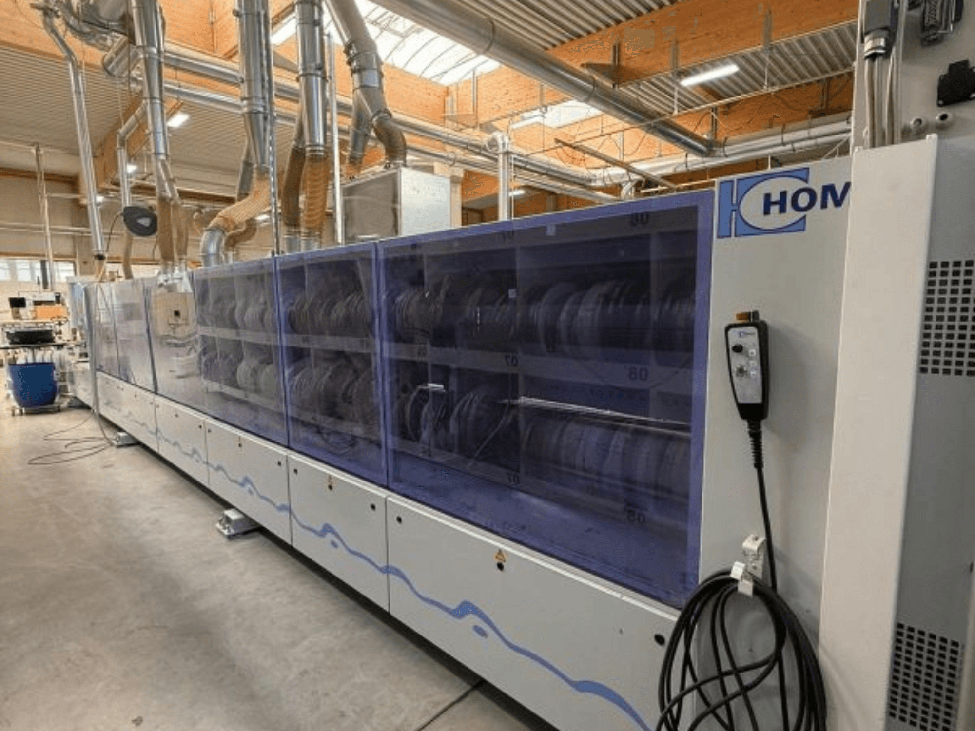 HOM industriële wasmachine, vooraanzicht, met transparant paneel dat vaatwerk toont; bedieningspaneel met knoppen aan de zijkant.