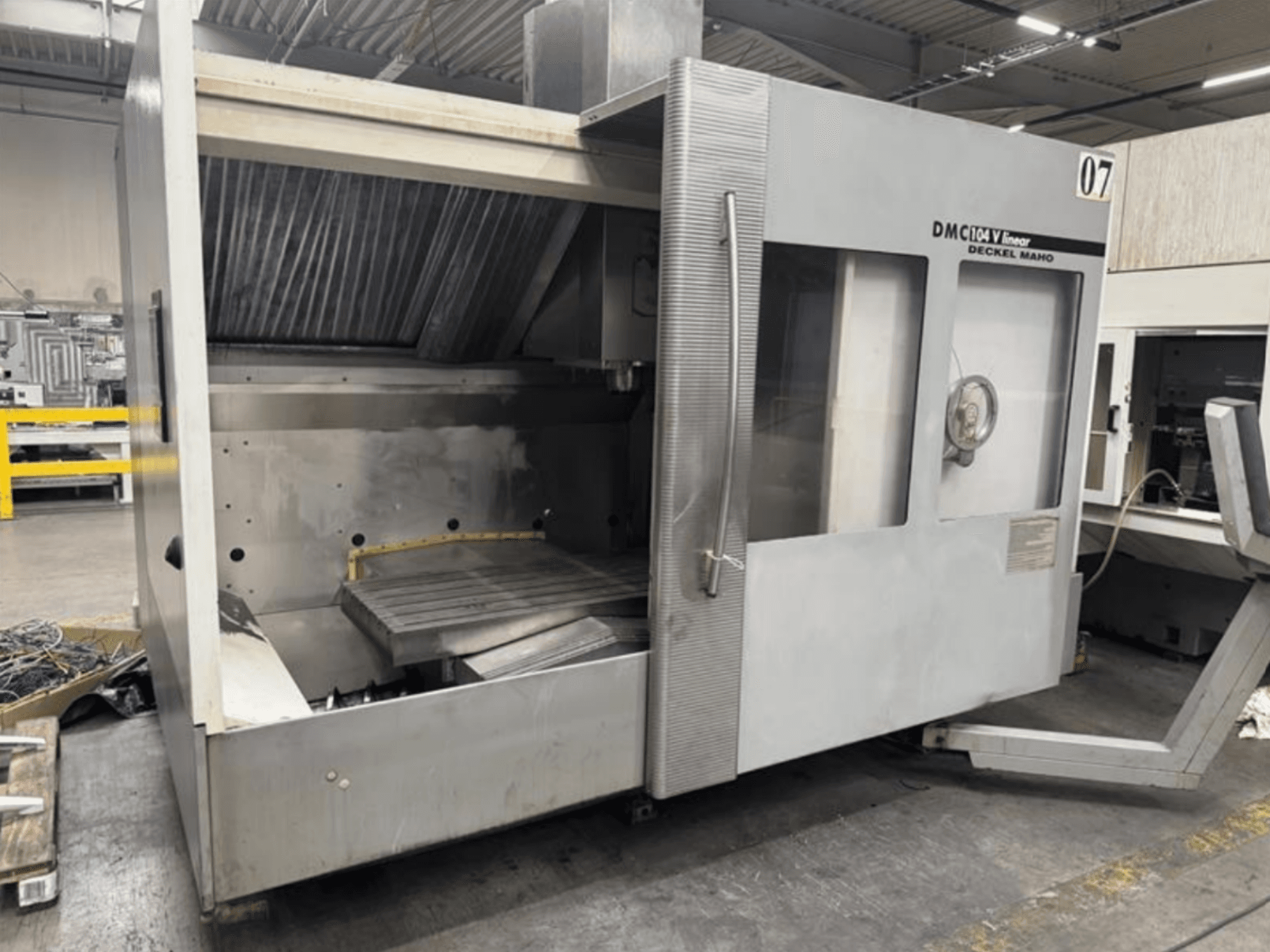 DMC 104 V lineaire machine van Deckel Maho, vooraanzicht, met een leeg bewerkingsgebied met een grote werktafel.