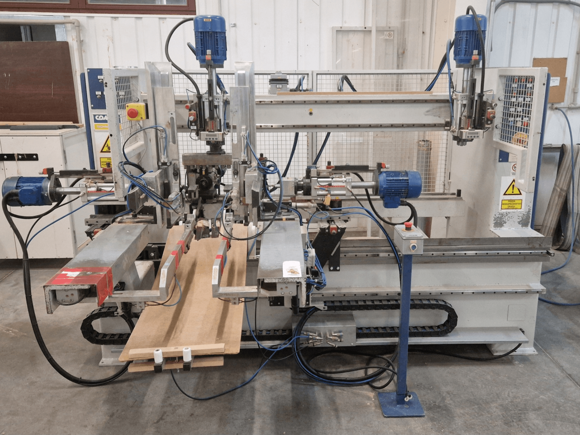 COMEC FMOV 1500 multi-spindel boormachine vooraanzicht, met dubbele spindels, bedieningspaneel en houtstuk in werking.