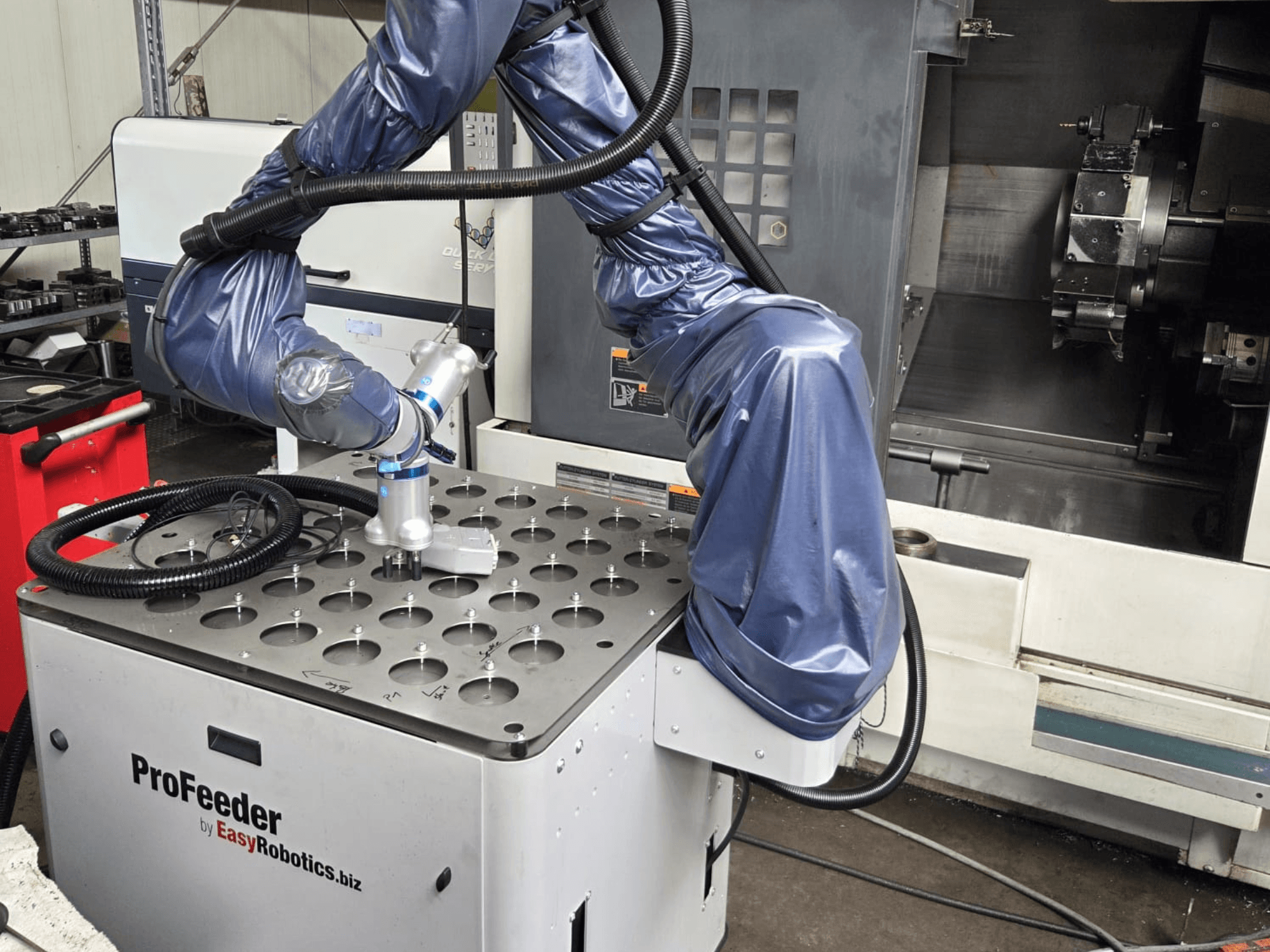 Samenwerkende robot EASYROBOTICS ProFeeder vanuit een vooraanzicht, met een robotarm gepositioneerd over een geperforeerde metalen tafel.