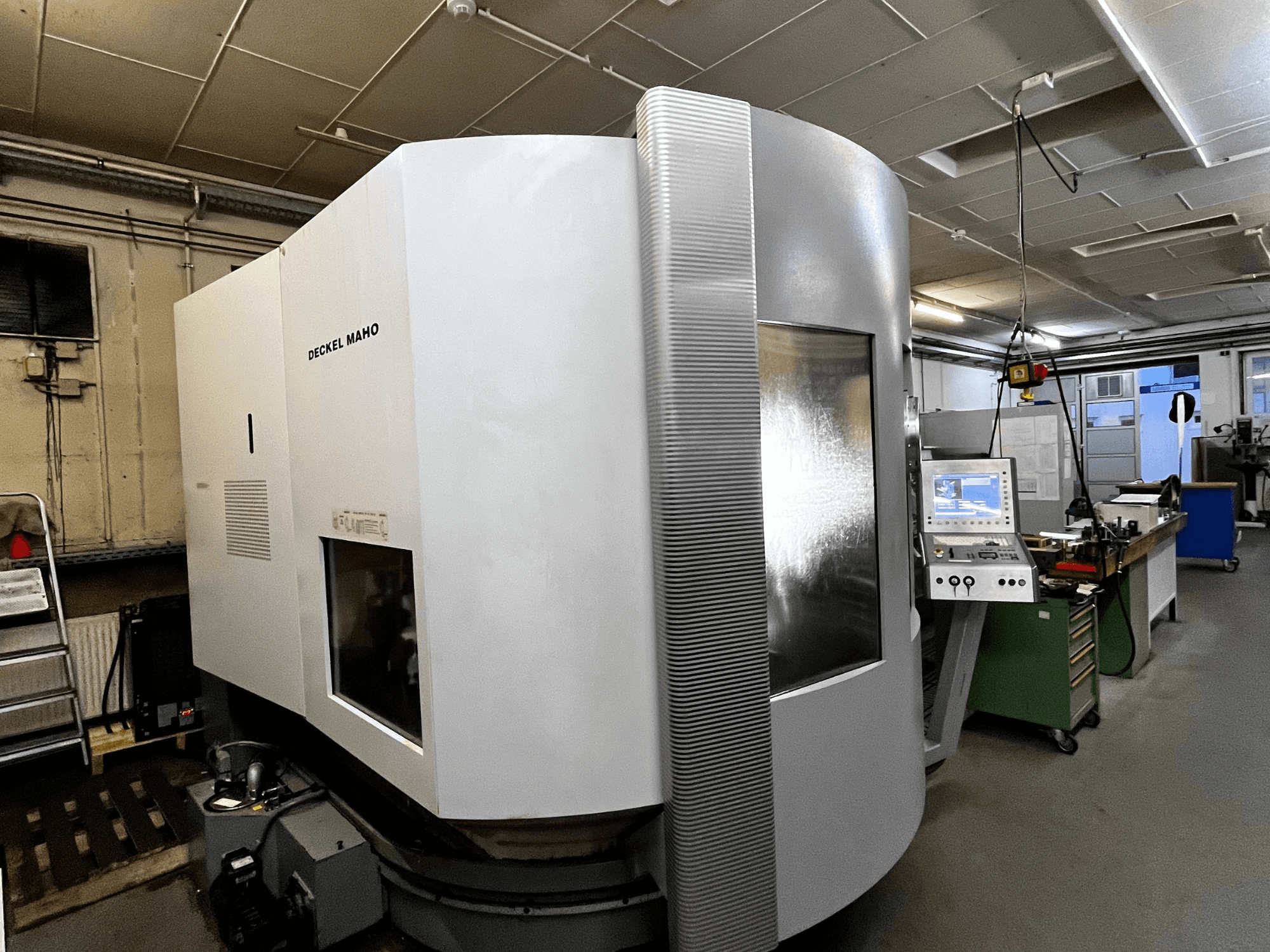 Deckel Maho CNC machine, vooraanzicht, witte buitenkant, bedieningspaneel zichtbaar, werkplaatsinstelling.