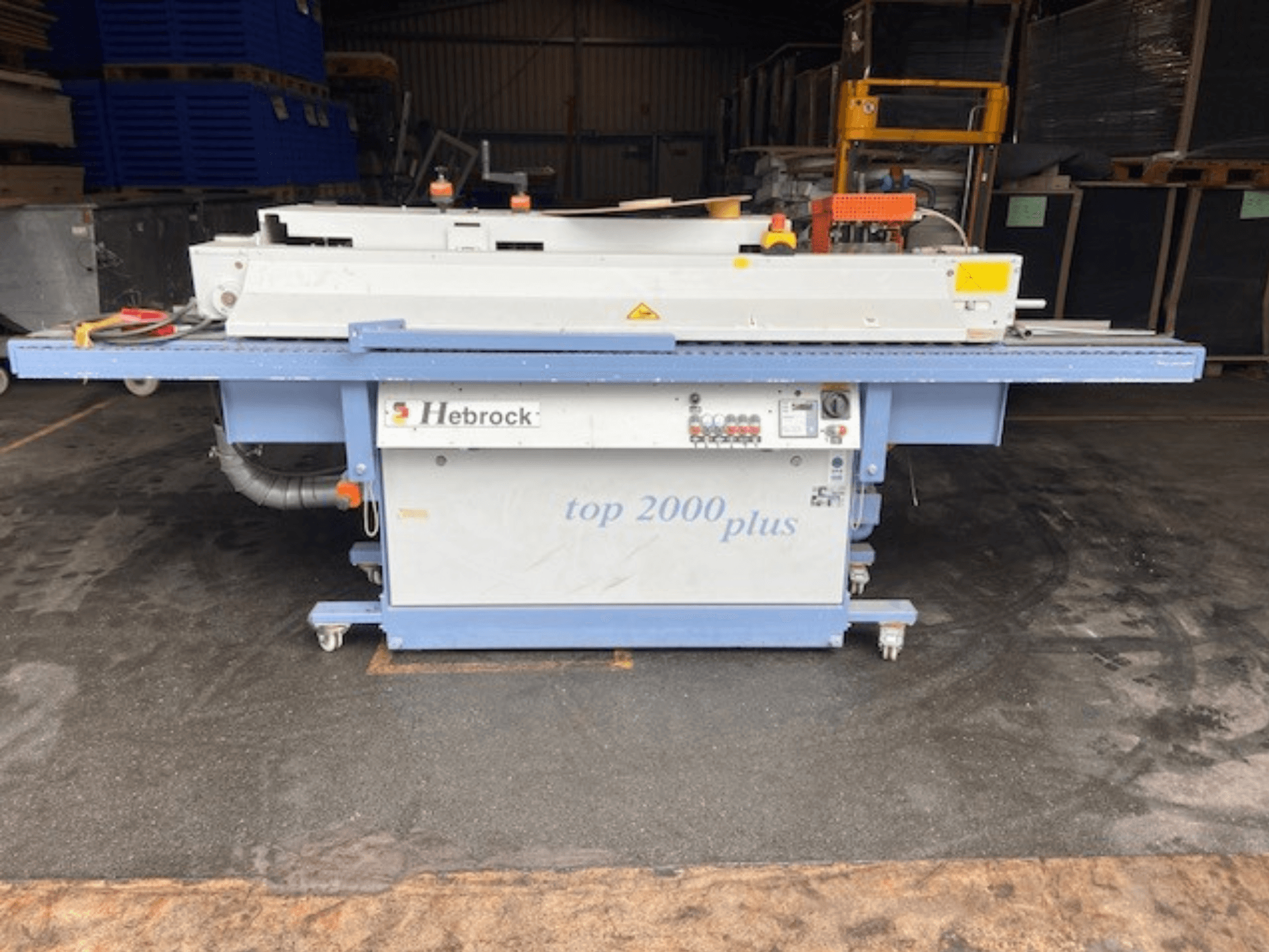 Hebrock Top 2000 Plus, vooraanzicht; industriële elektrische machine met bedieningspaneel, wielen voor mobiliteit en veiligheidslabels zichtbaar.