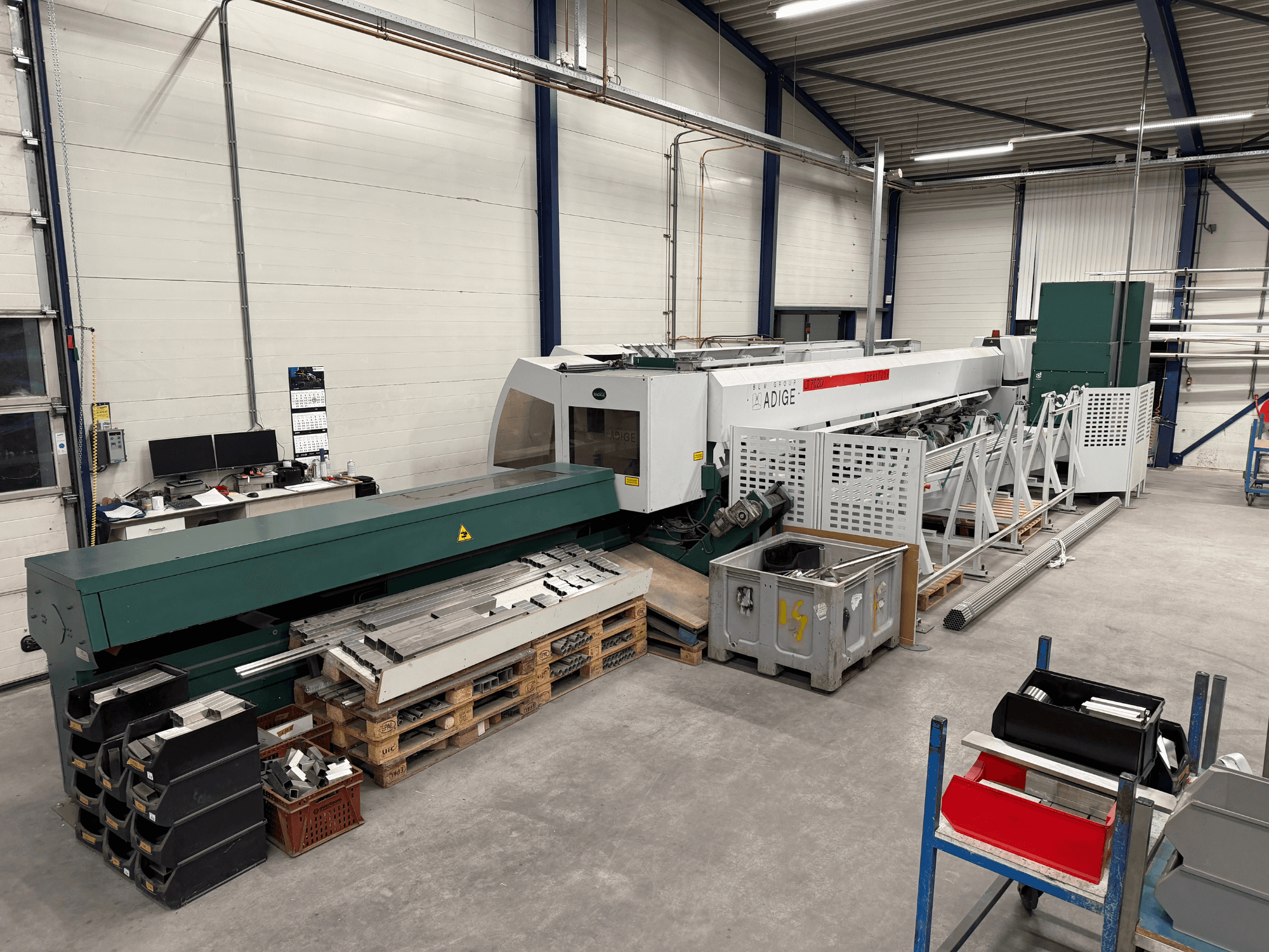 BLM Adige LT702 CO₂-lasersnijmachine in een werkplaats, zijaanzicht waarbij metalen onderdelen en rommel op de werkplek zichtbaar zijn.