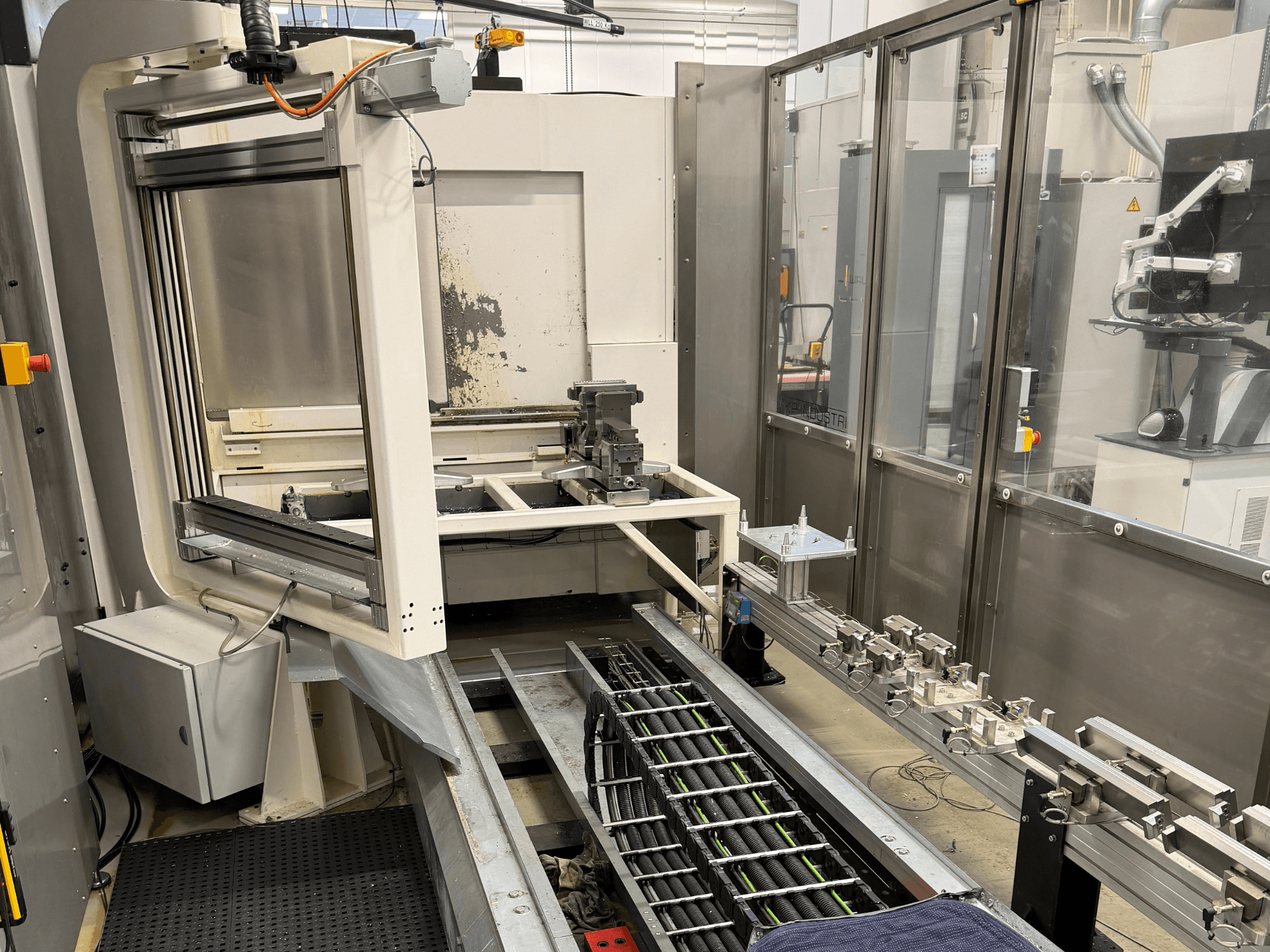 Geautomatiseerd industrieel werkstation met een robotarm, railsysteem en bedieningspaneel in zijaanzicht.