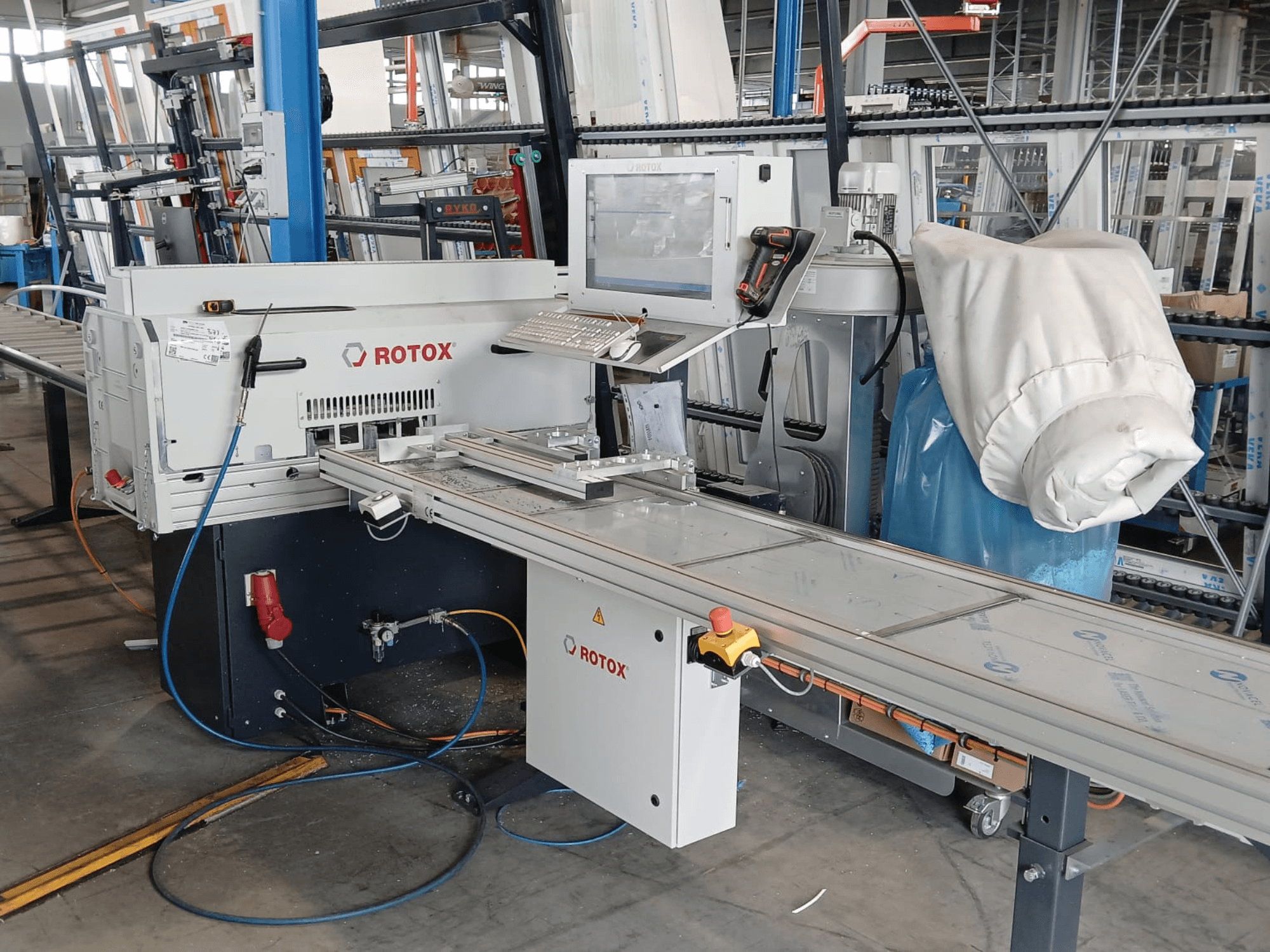 Vooraanzicht van een Rotox GLA401-kunststofverwerkingsmachine met bedieningspaneel, transportband en zichtbare slangen in een industriële omgeving.