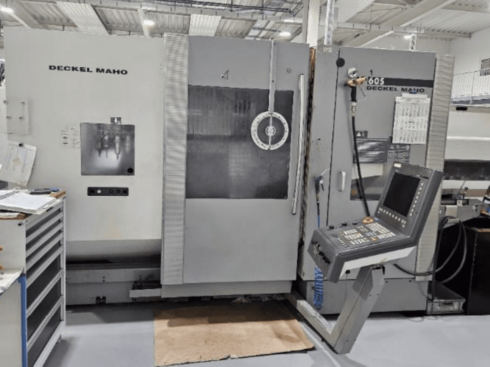 Vooraanzicht van een DECKEL MAHO 60S CNC machine met bedieningspaneel, gereedschappen zichtbaar, in een werkplaats.