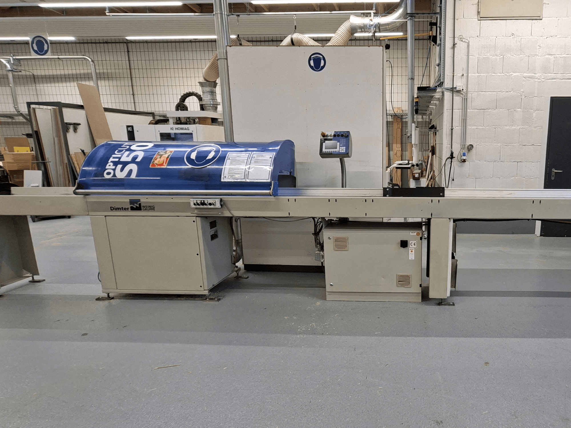Dimter OptiCut S50 houtsnijmachine in zijaanzicht, met een blauwe behuizing, bedieningspaneel en transportband.