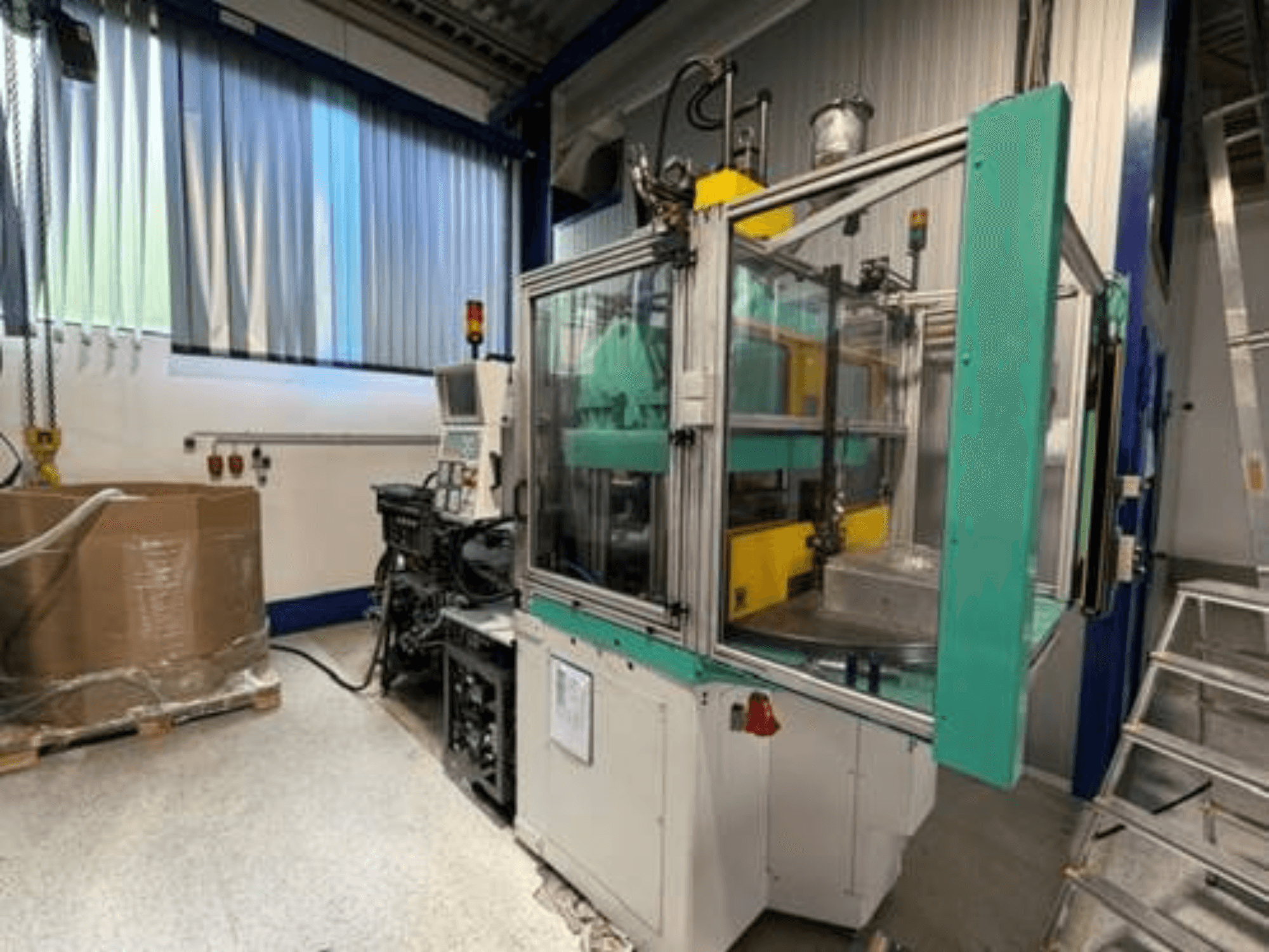 Arburg 1200 TS 800-60-350 verticale spuitgietmachine, zijaanzicht, met bedieningspaneel en doorzichtige veiligheidsbehuizing.