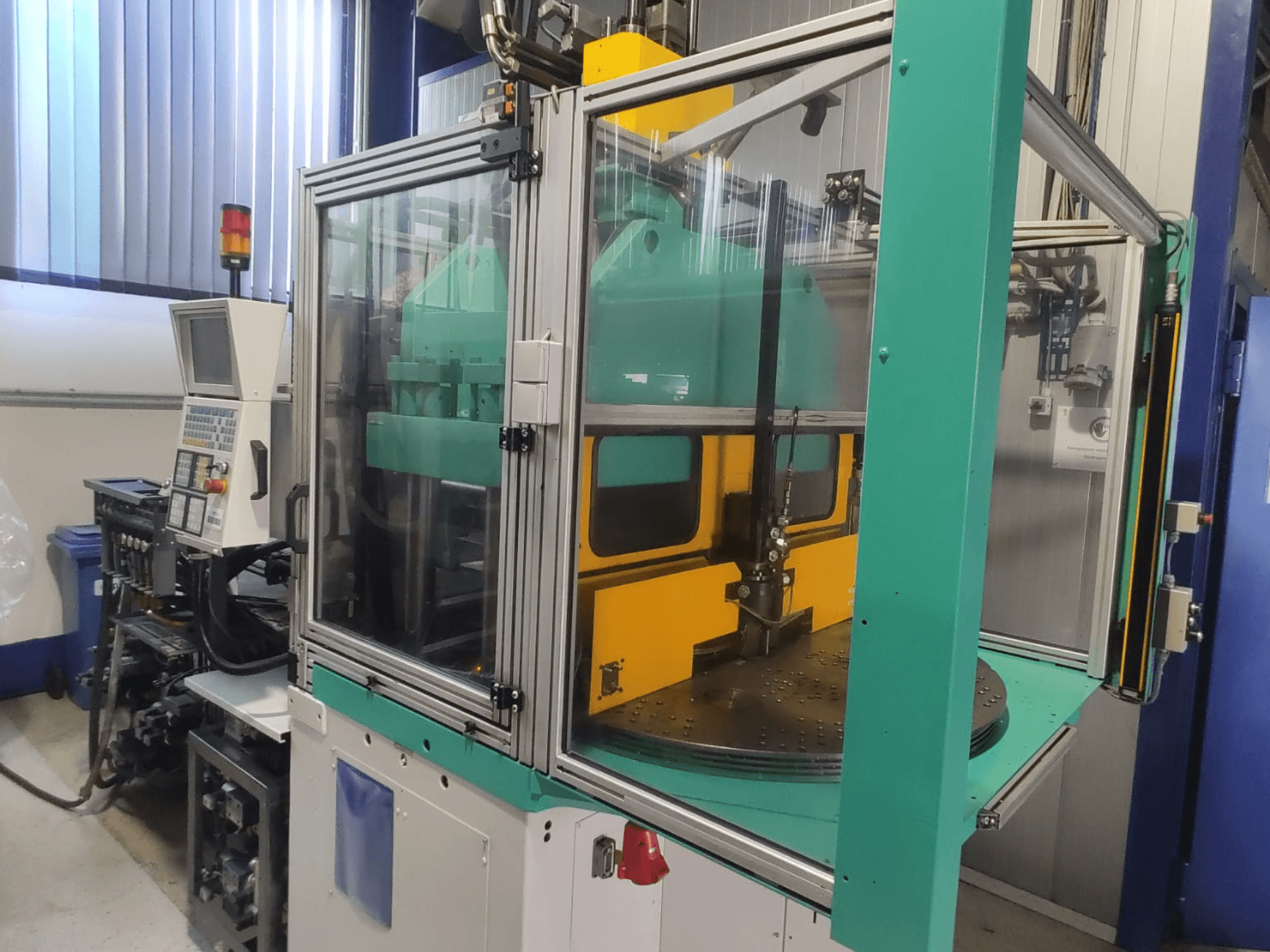 Arburg 1200 TS 800-60-350 verticale spuitgietmachine, vooraanzicht met het bedieningspaneel en de veiligheidsbehuizing.