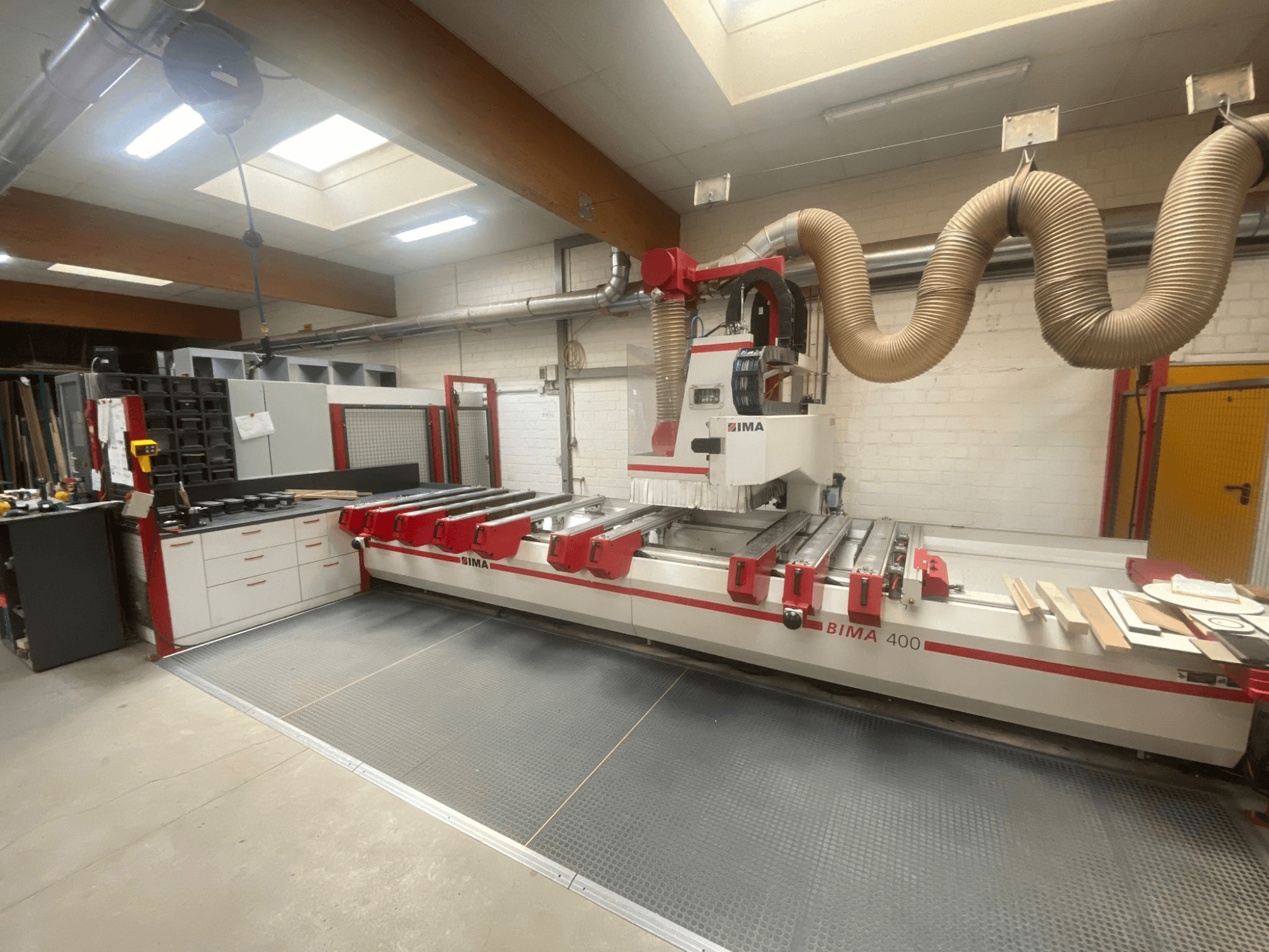 BIMA 400 CNC machine gezien vanaf de voorkant, met een rood en wit ontwerp en een stofafzuigsysteem.