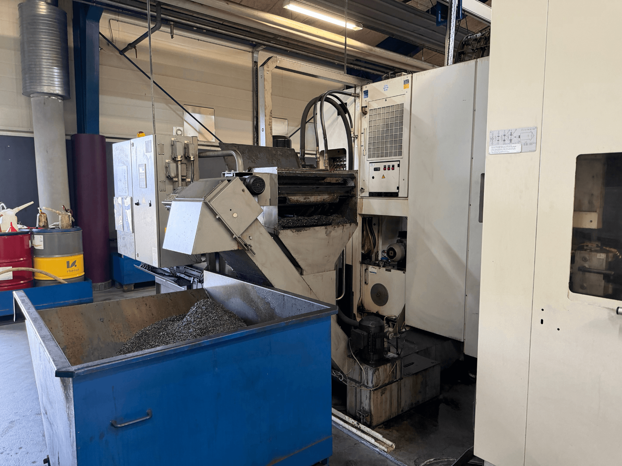 Vooraanzicht van het horizontale bewerkingscentrum HELLER MCH 250 met de bak voor het recyclen van metaalkoelmiddel en het bedieningspaneel zichtbaar.