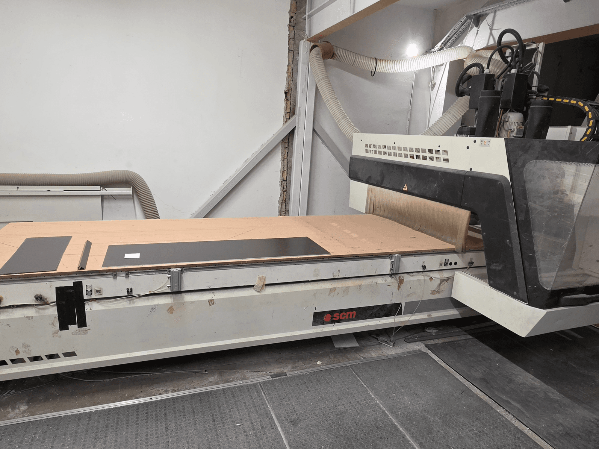 SCM RECORD 132 CNC-houtbewerkingscentrum in zijaanzicht, met een vlakke werktafel met zwarte werkstukken en een stofafzuigsysteem.