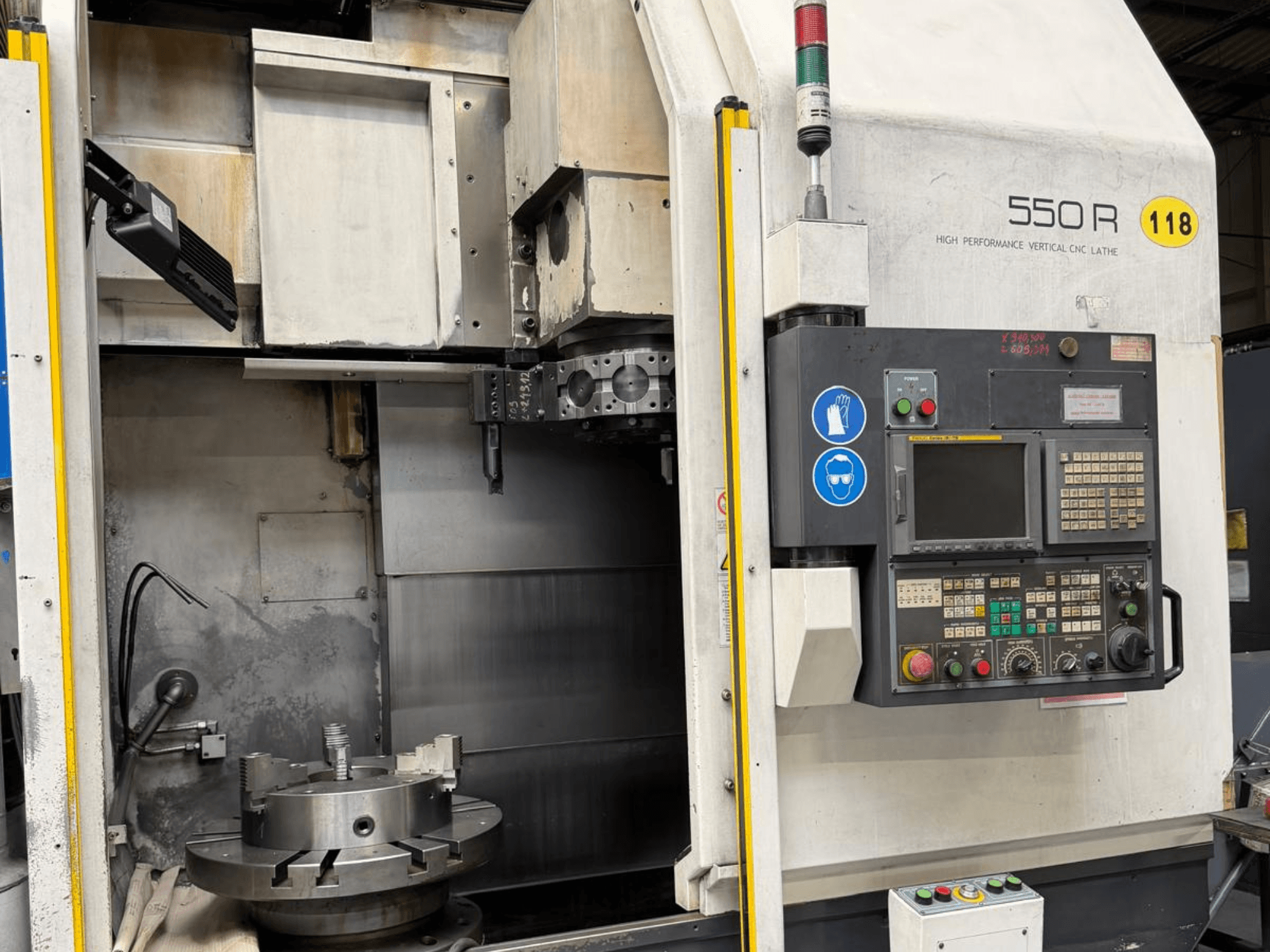 High Performance Vertical CNC Lathe 550 R, vooraanzicht, met bedieningspaneel, draaibare klauwplaat en operationele onderdelen.