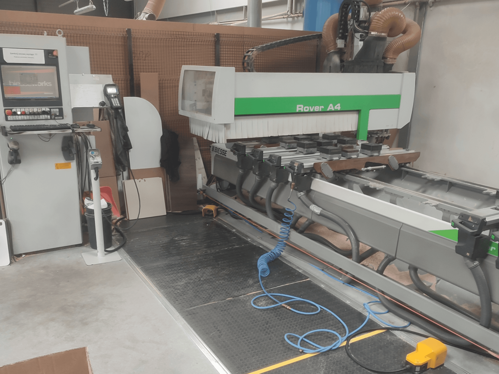 BIESSE Rover A4 CNC-houtbewerkingscentrum in zijaanzicht, met het bedieningspaneel, de vacuümklemmen en het stofafzuigsysteem.